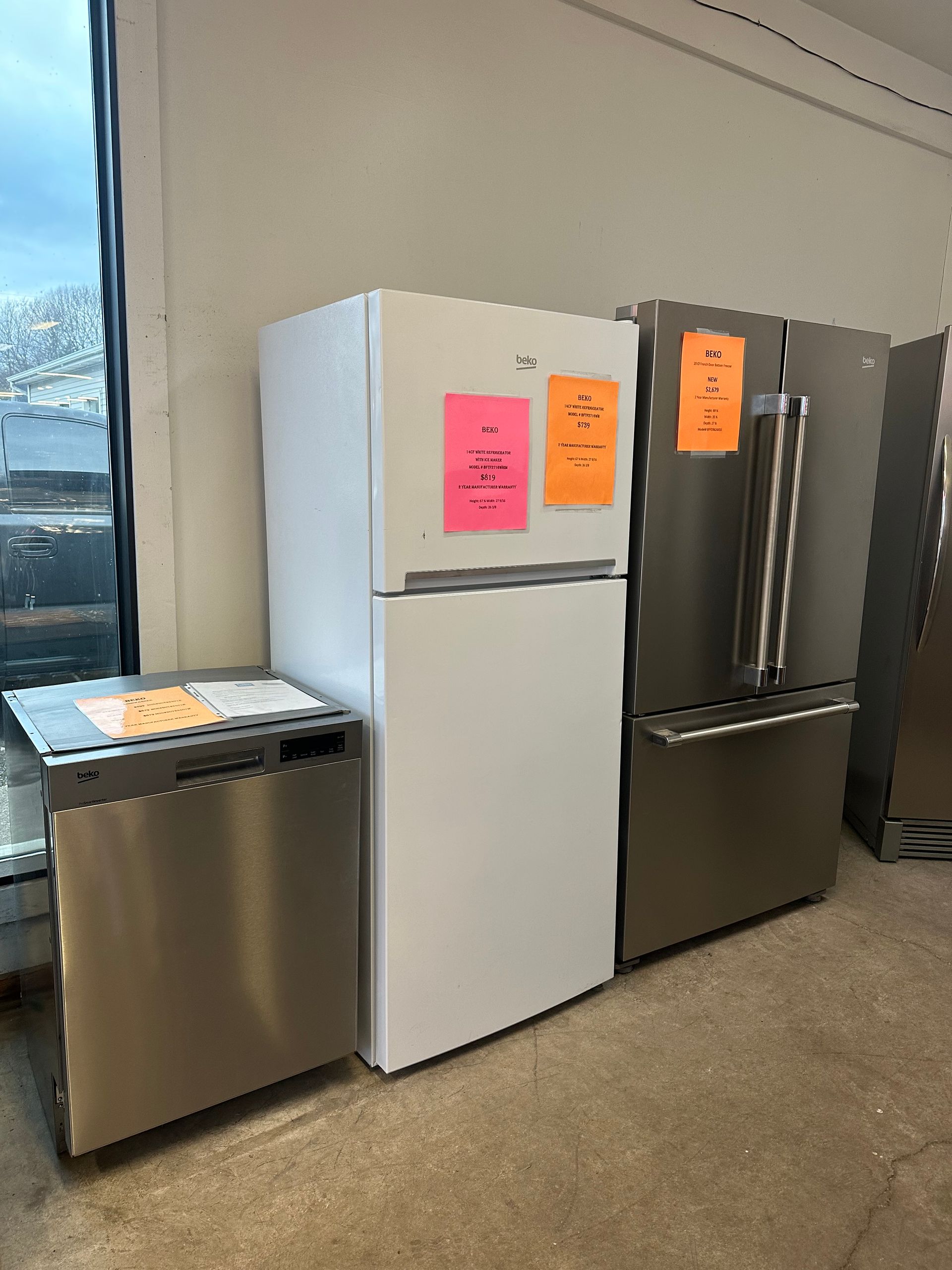 A white refrigerator is sitting next to a stainless steel dishwasher.