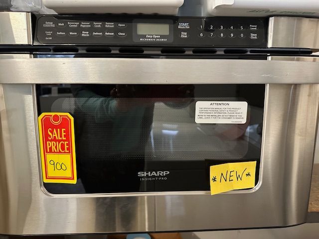 A stainless steel microwave oven with a sale price tag on it