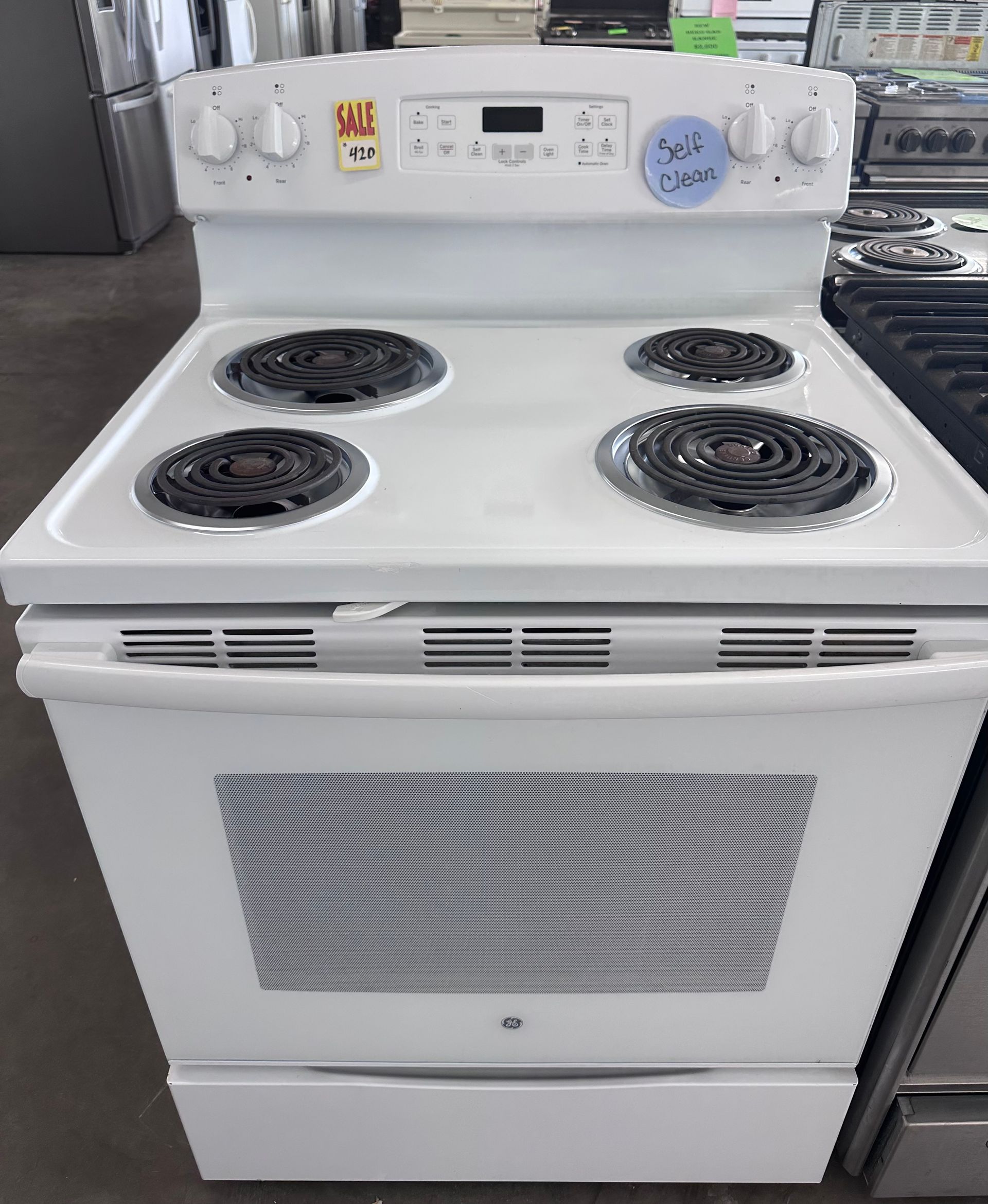 White electric stove with four burners, oven, and storage drawer.