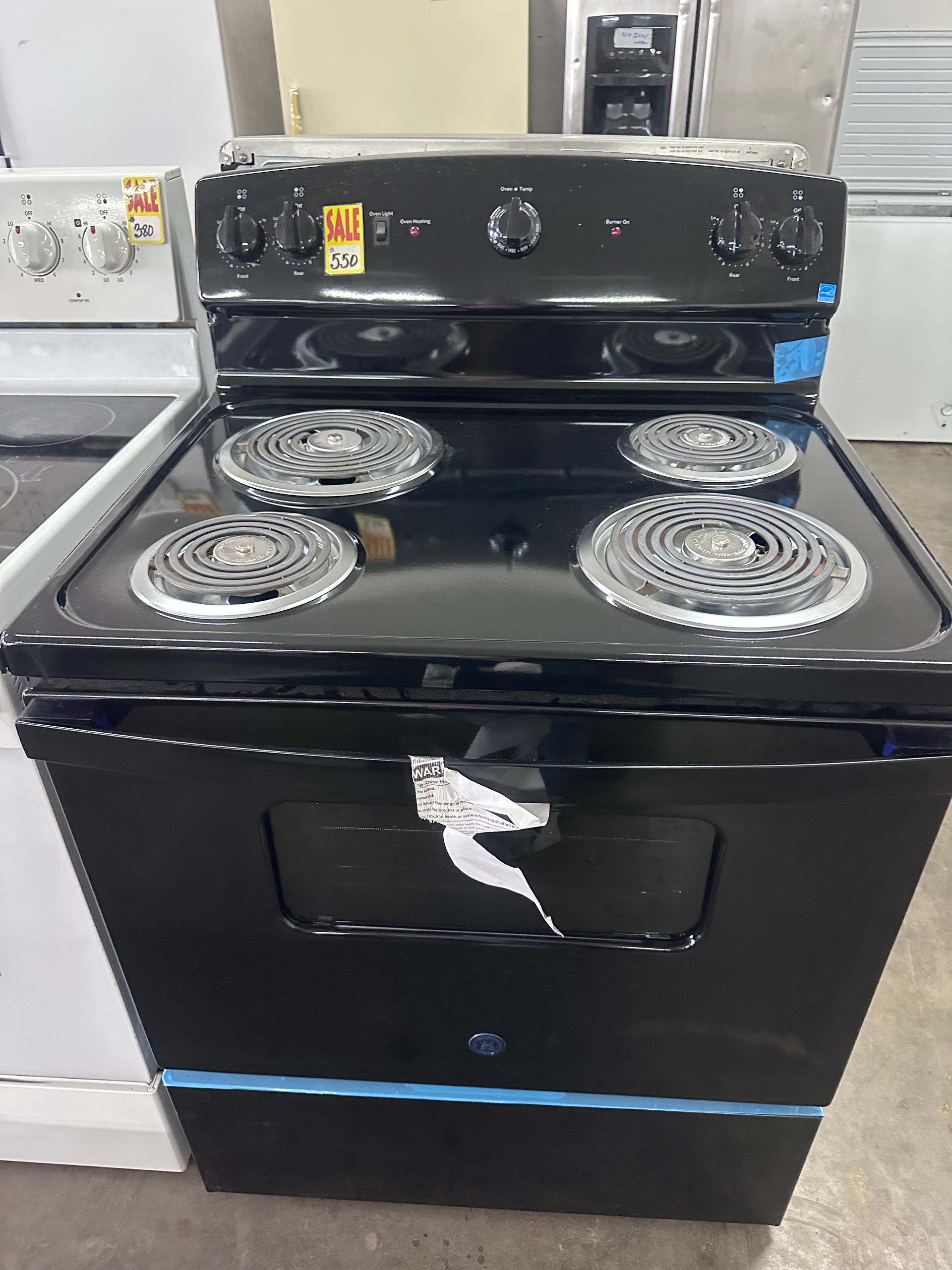 Black electric stove with coil burners and oven door in a kitchen, front control panel visible