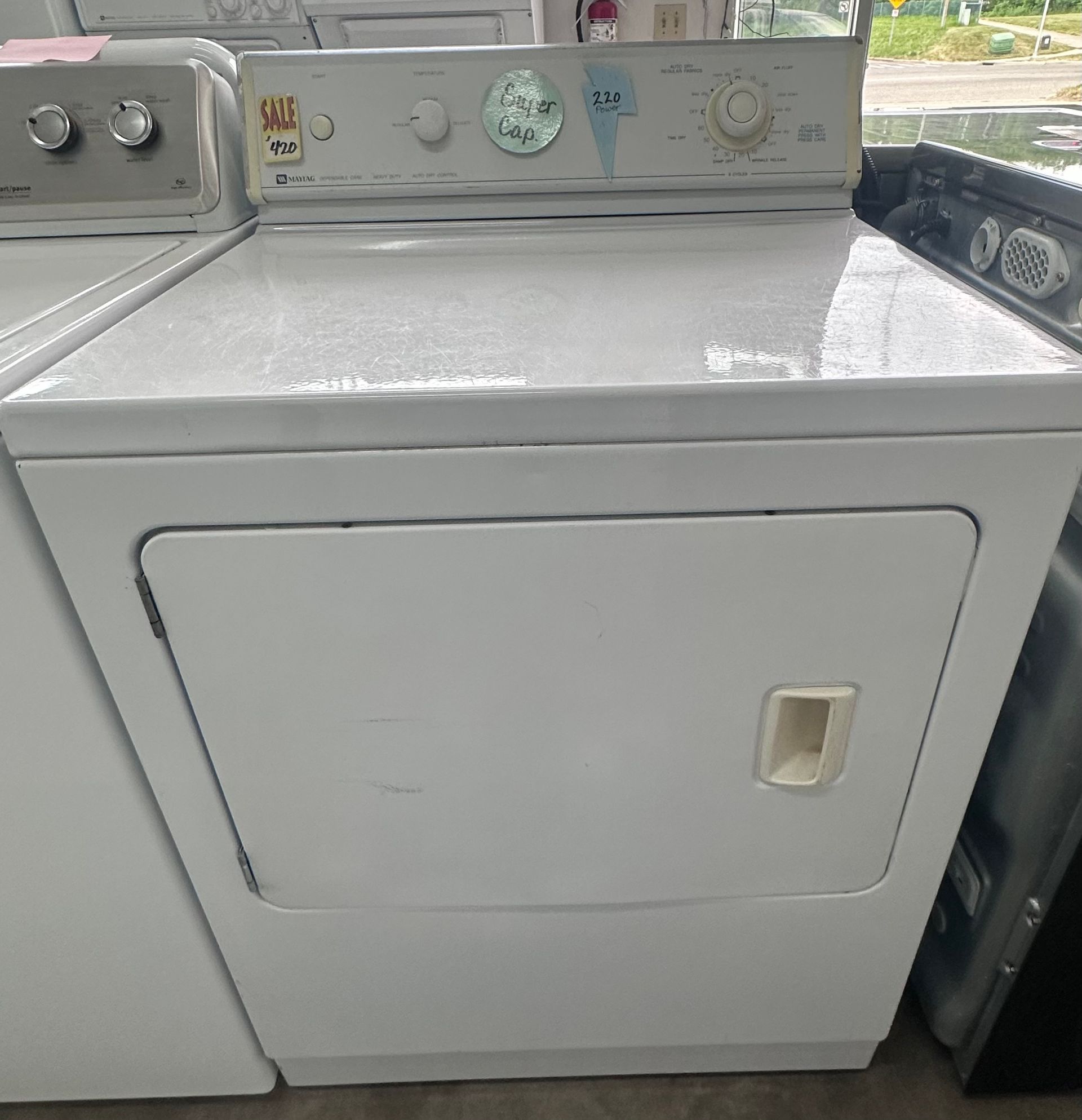 A white dryer is sitting on top of a counter in a laundry room.