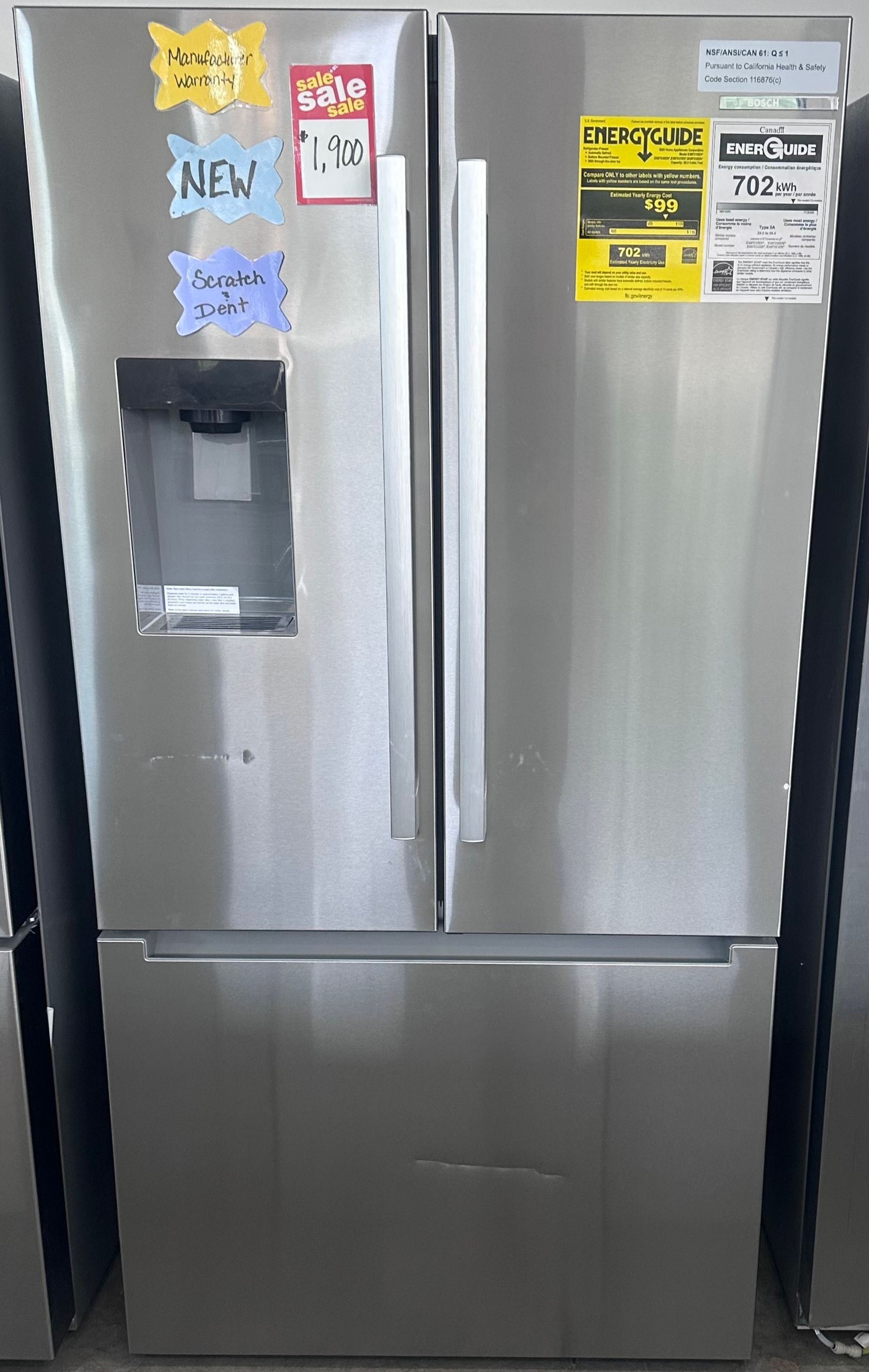 Stainless steel French door refrigerator with water dispenser and sale tags in an appliance store