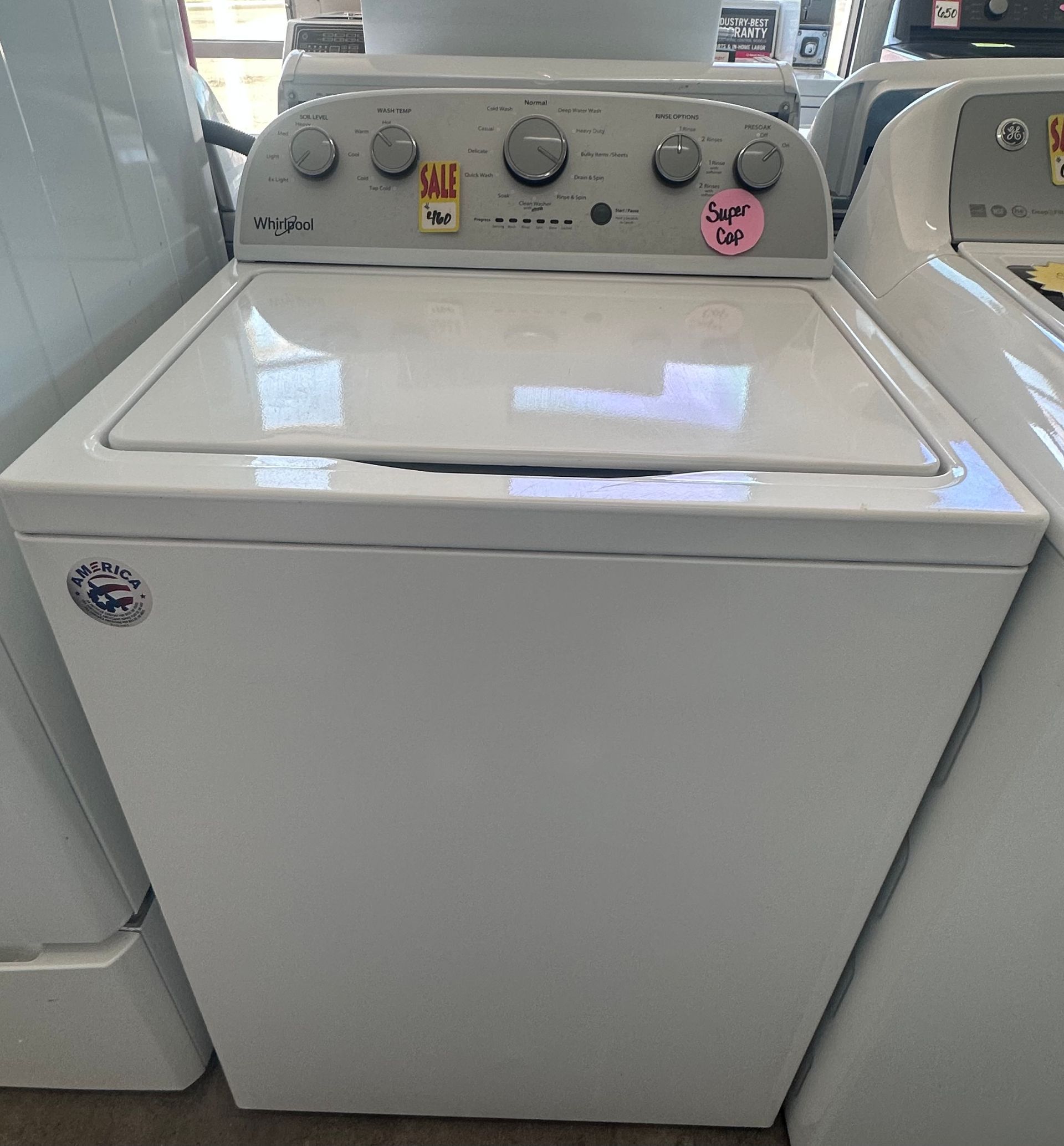 White GE top-load washing machine with controls on the top panel.