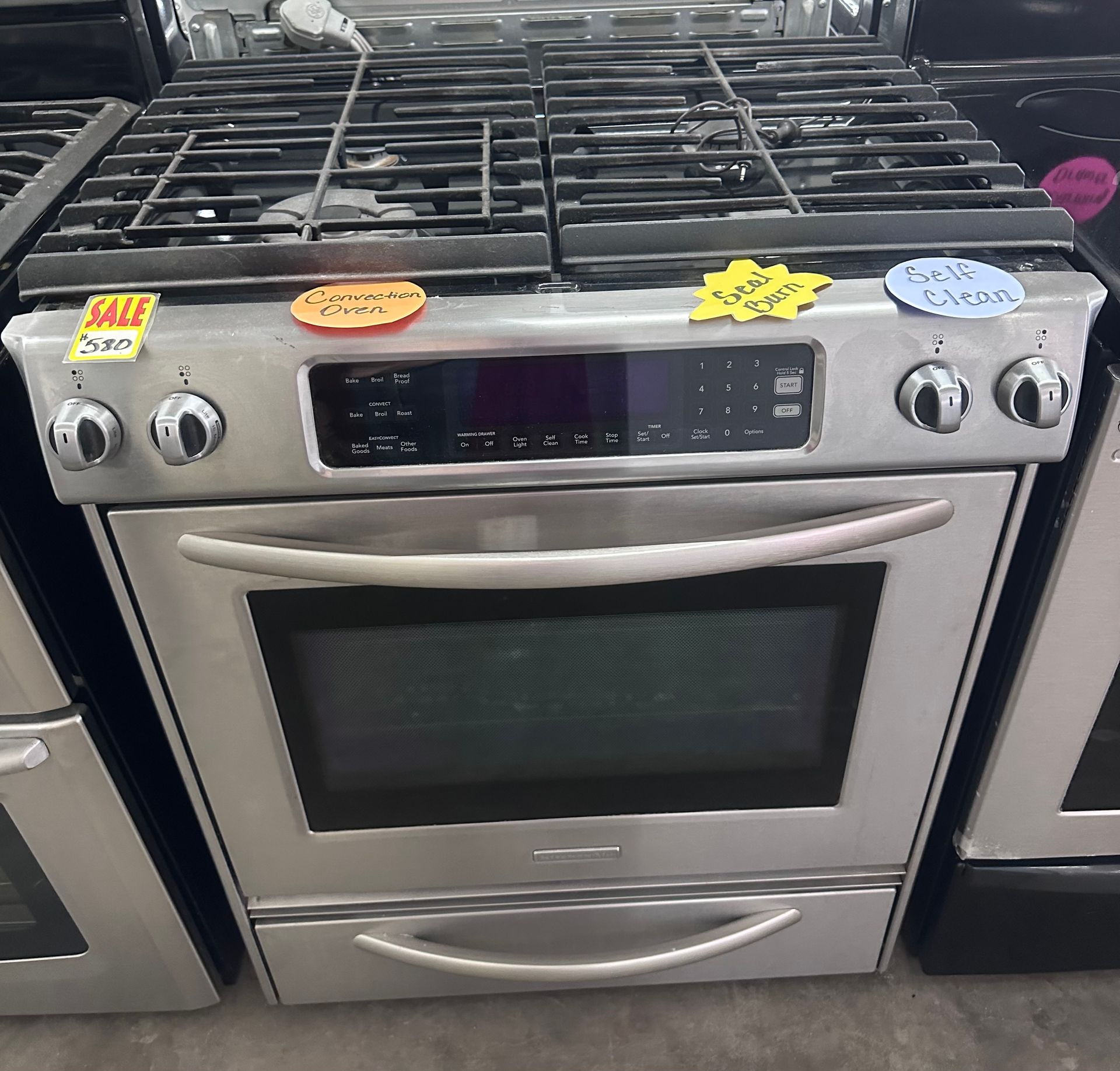 Stainless steel gas range oven with digital controls in an appliance store display