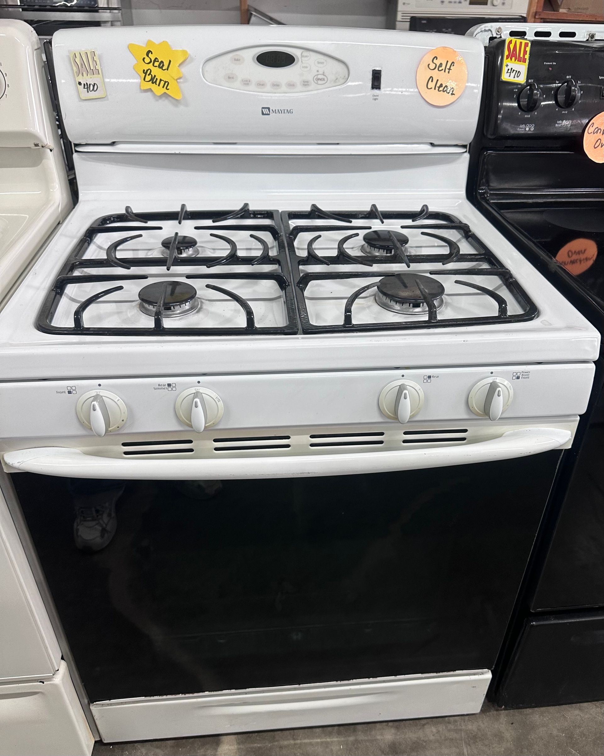 White gas stove with oven in a kitchen, with four burners and sticker decorations on the back panel