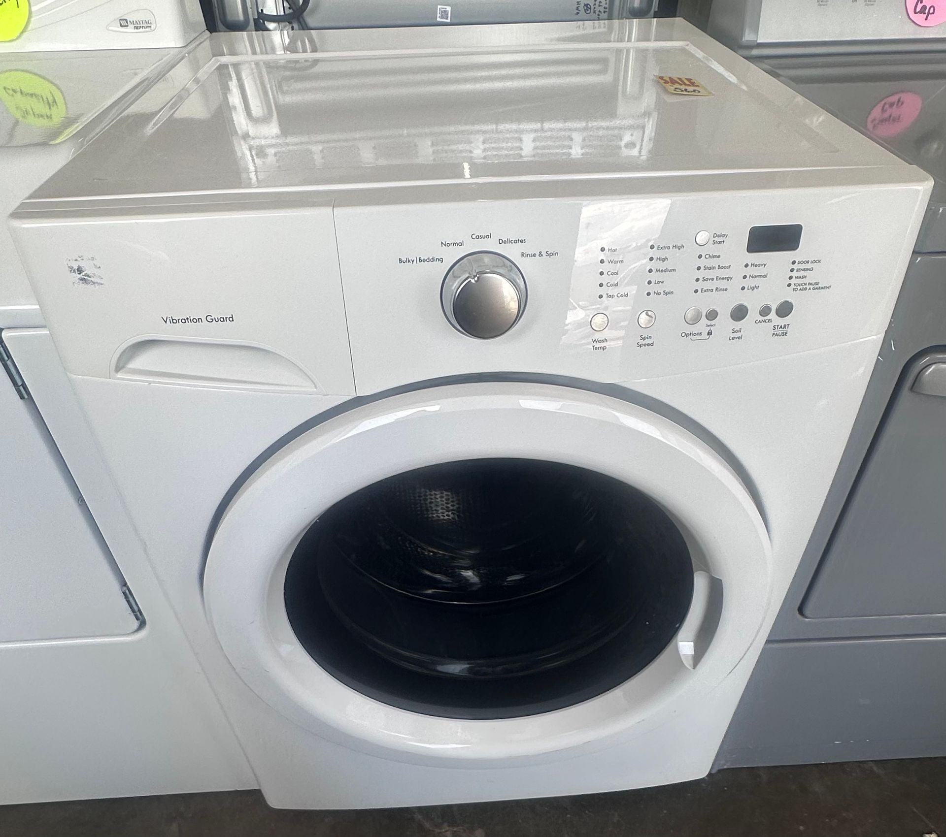 White front-loading washing machine with a round door and control dial in a laundry appliance display.