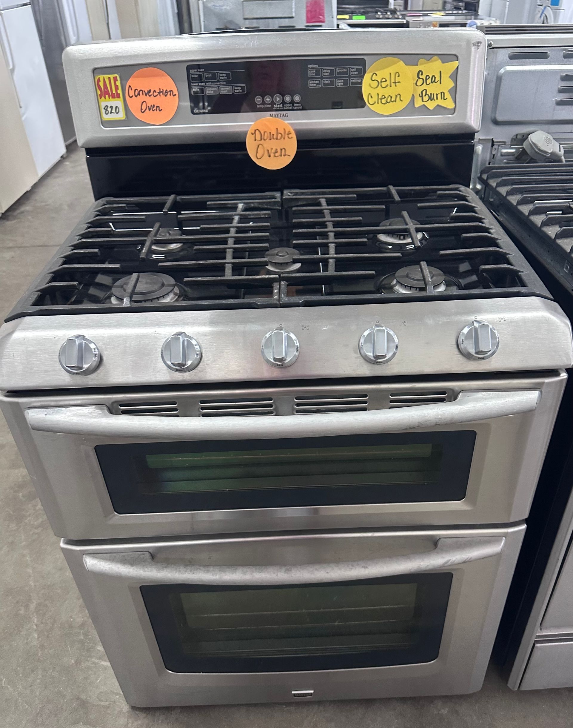 Stainless steel gas range with oven and control knobs in a store display.