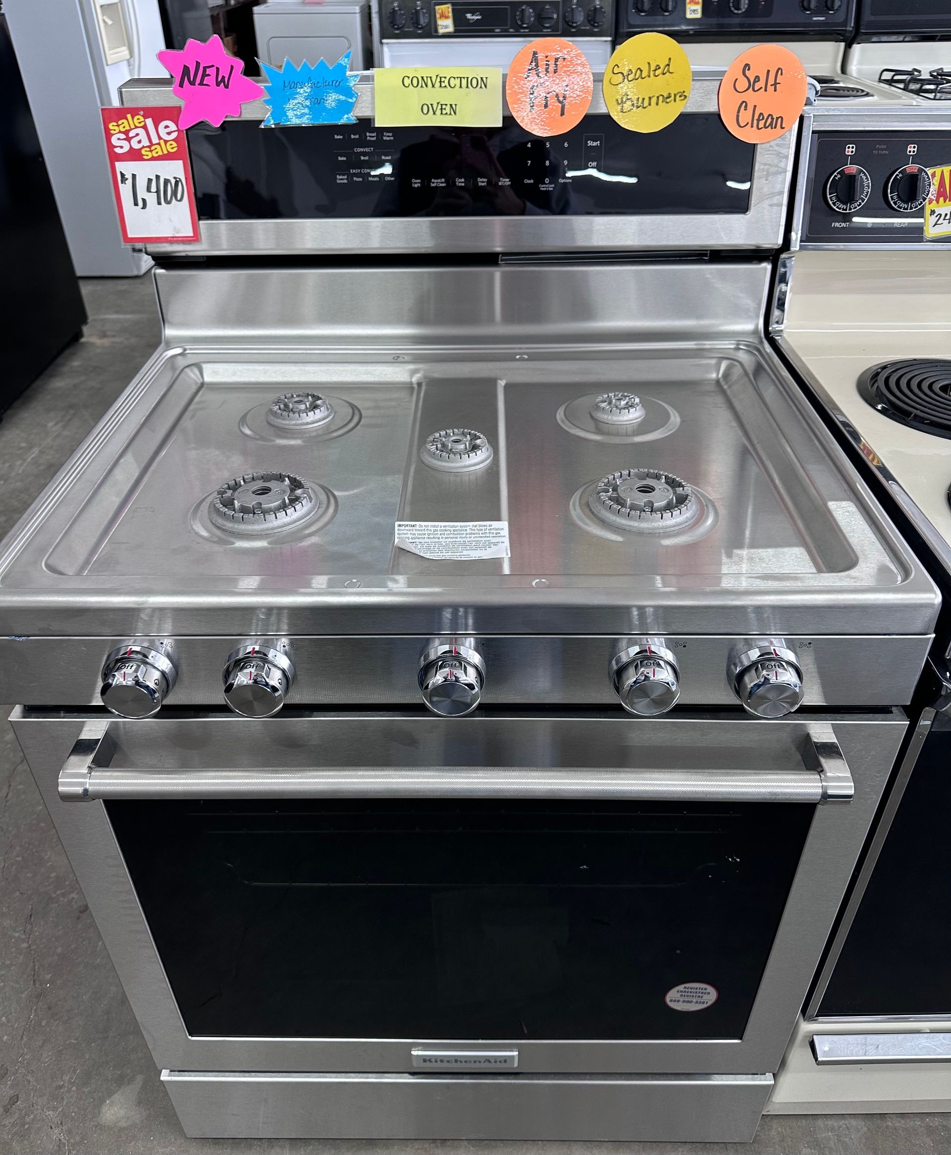 Stainless steel gas range with four burners, oven, and control knobs.