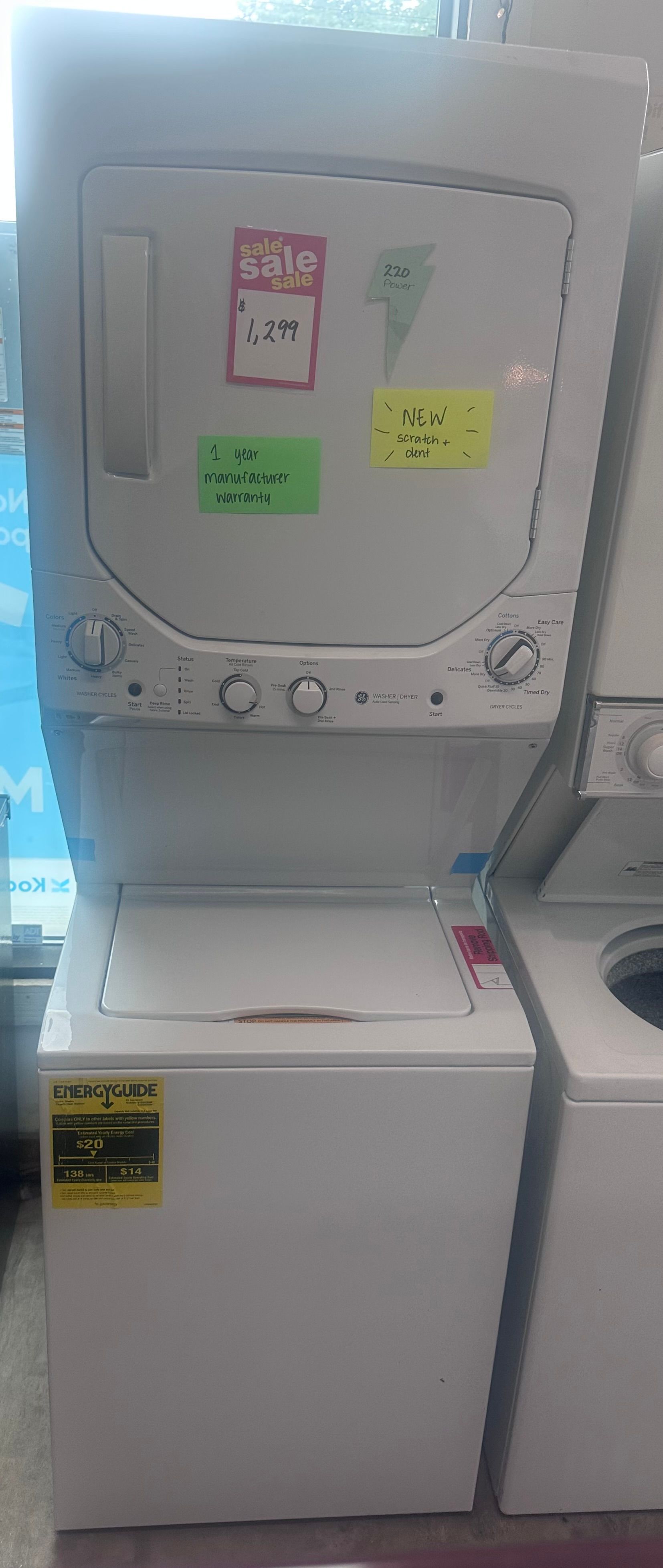 Small white machine with a top hatch and sticky notes, standing on a white cabinet in a bright room