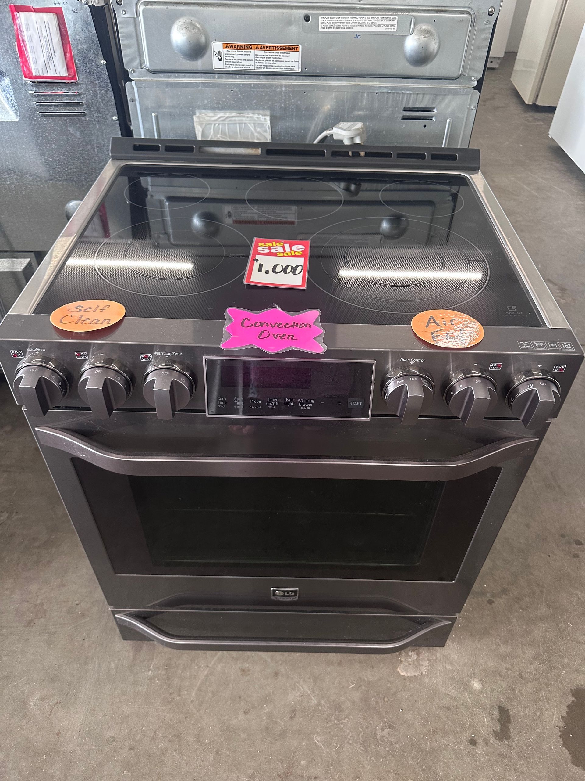 A black stove with a glass top is sitting on a concrete floor.
