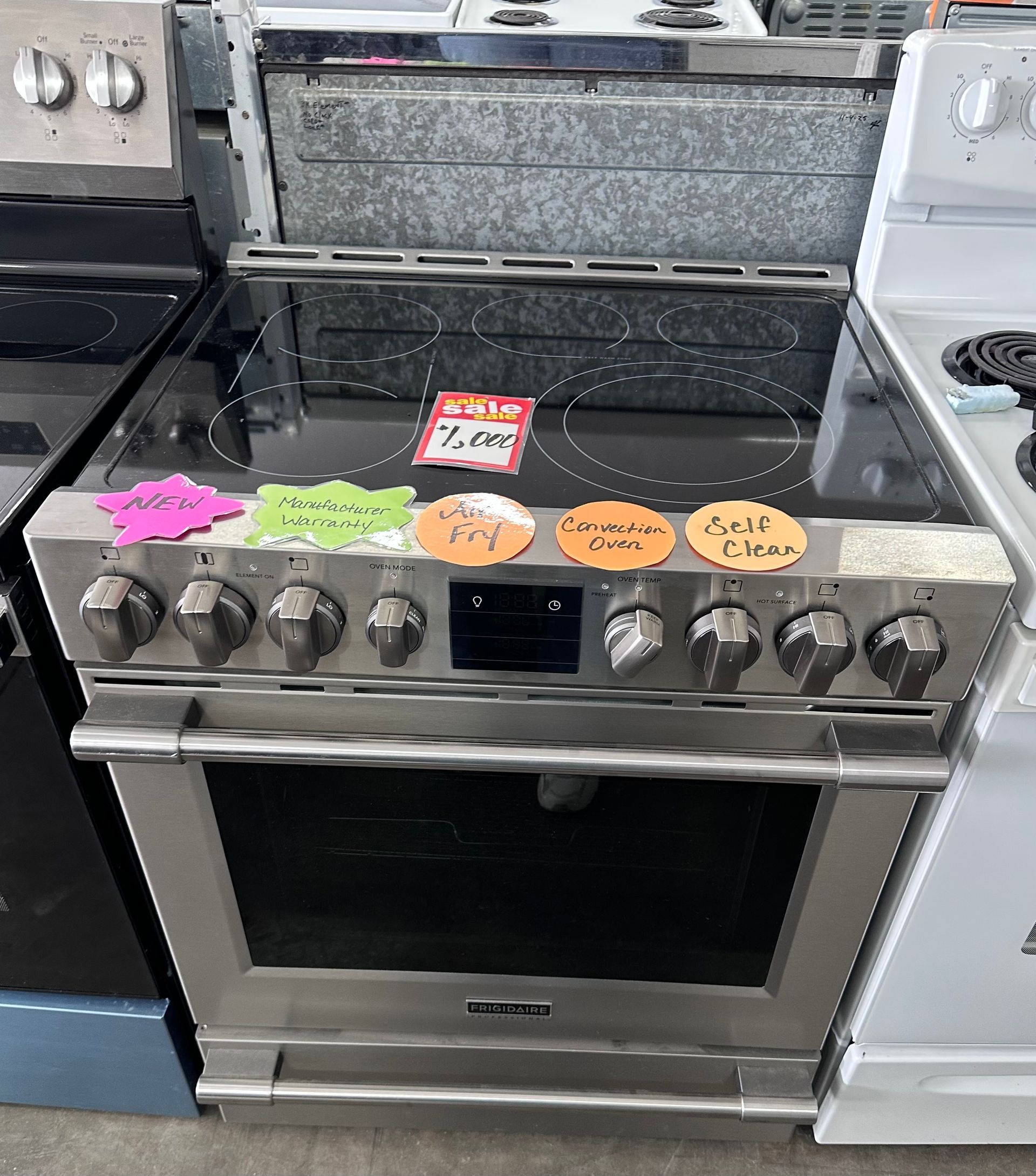 Stainless steel electric range with glass cooktop and various price tags.