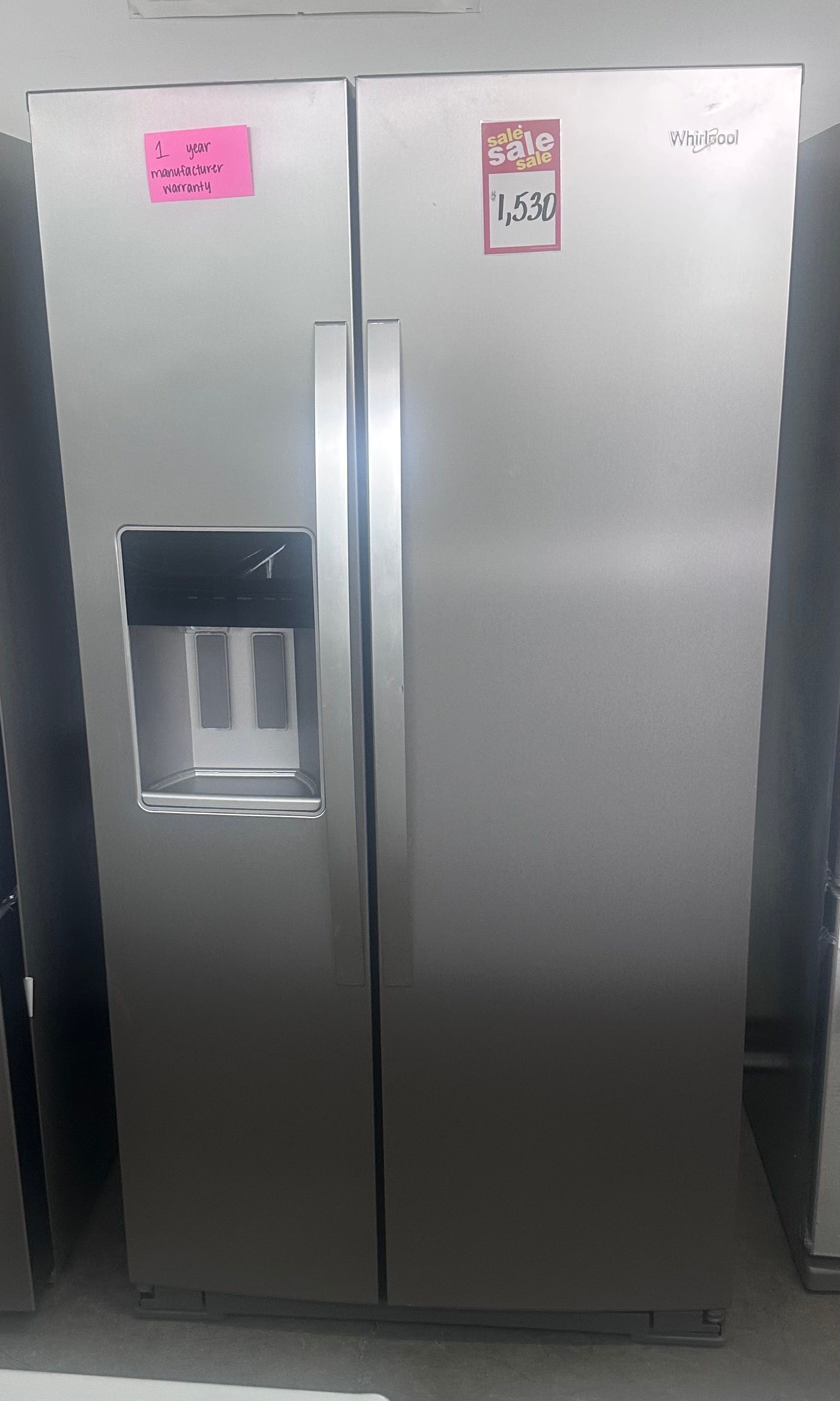A stainless steel side-by-side refrigerator with a water dispenser, taped doors, and price labels attached.