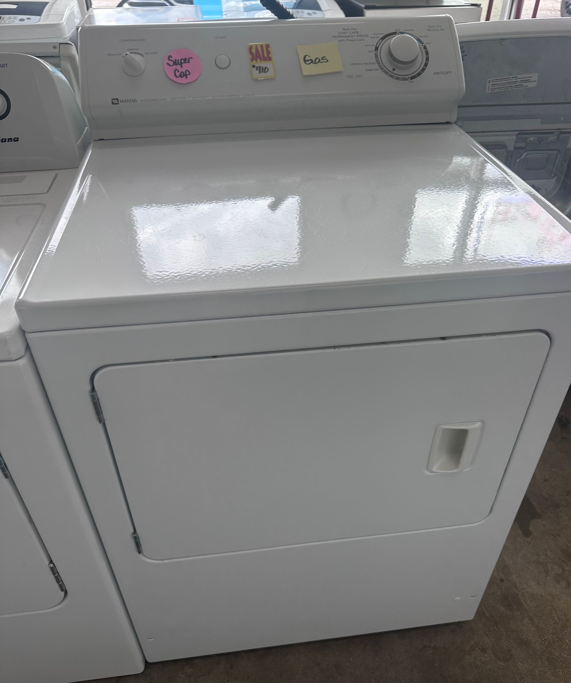 White clothes dryer with top control panel and front door in a laundry area