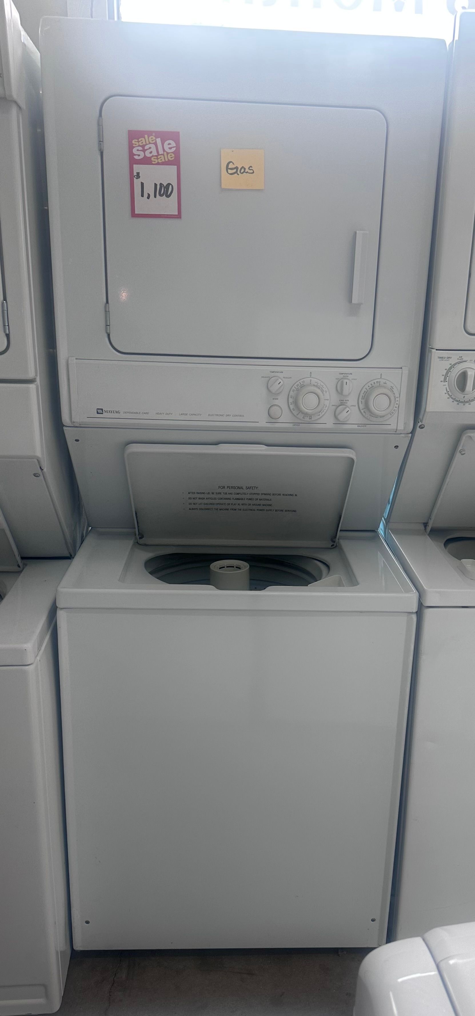 Stacked apartment laundry machines in a small utility room, white washer below and dryer above.