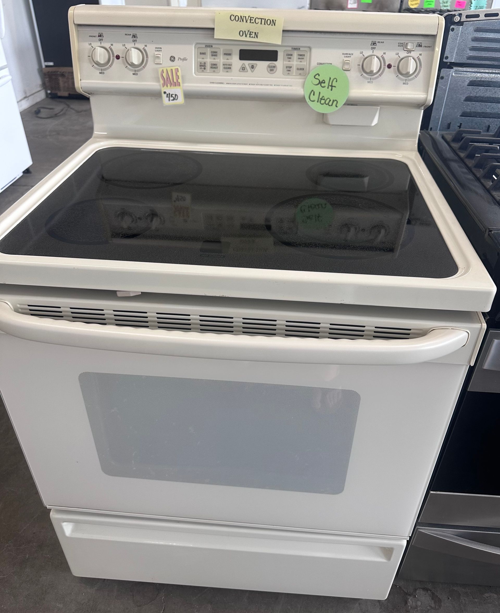 A white stove with a green tag on it that says ' always ' on it.