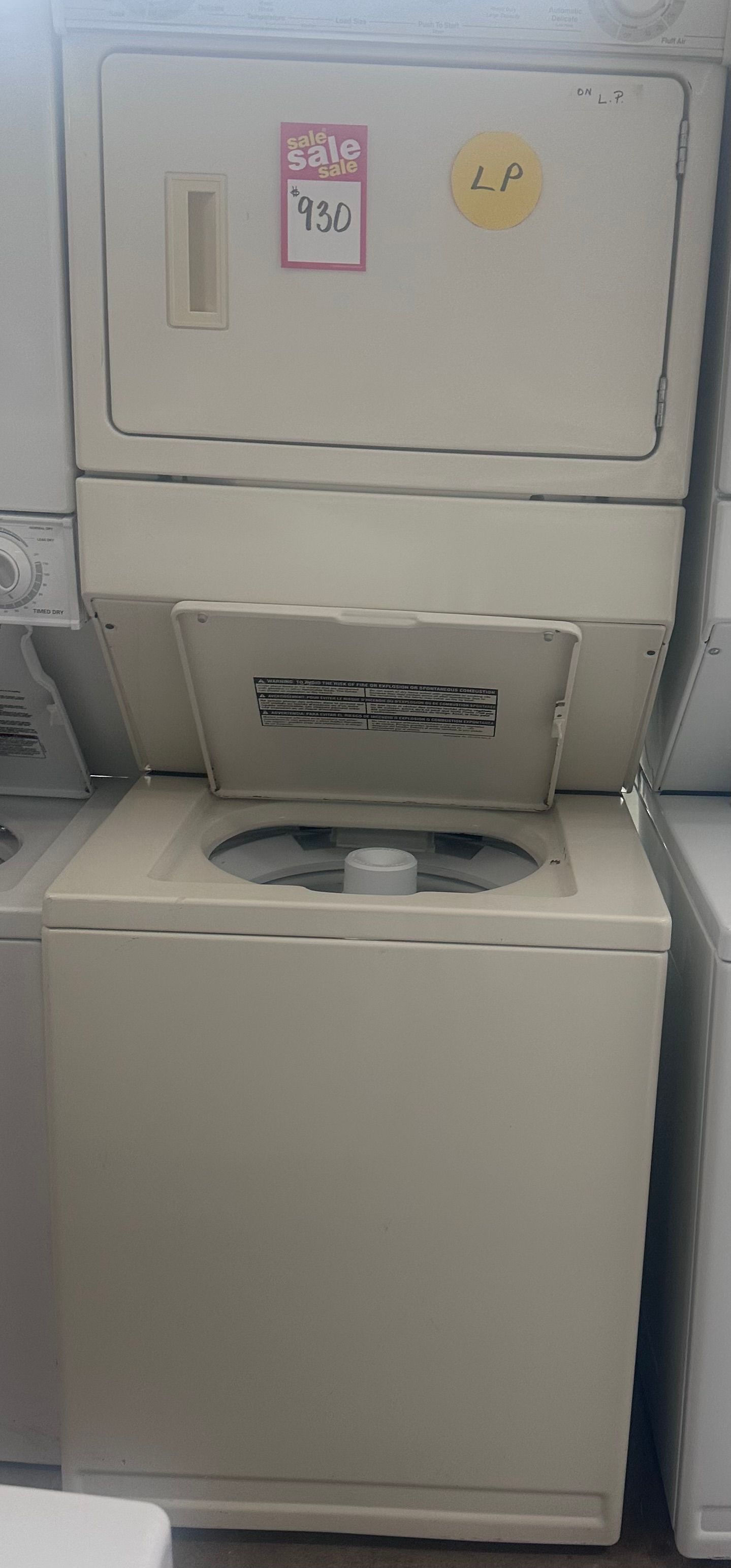 White stacked washer and dryer in a laundry room, with small stickers on the upper door.