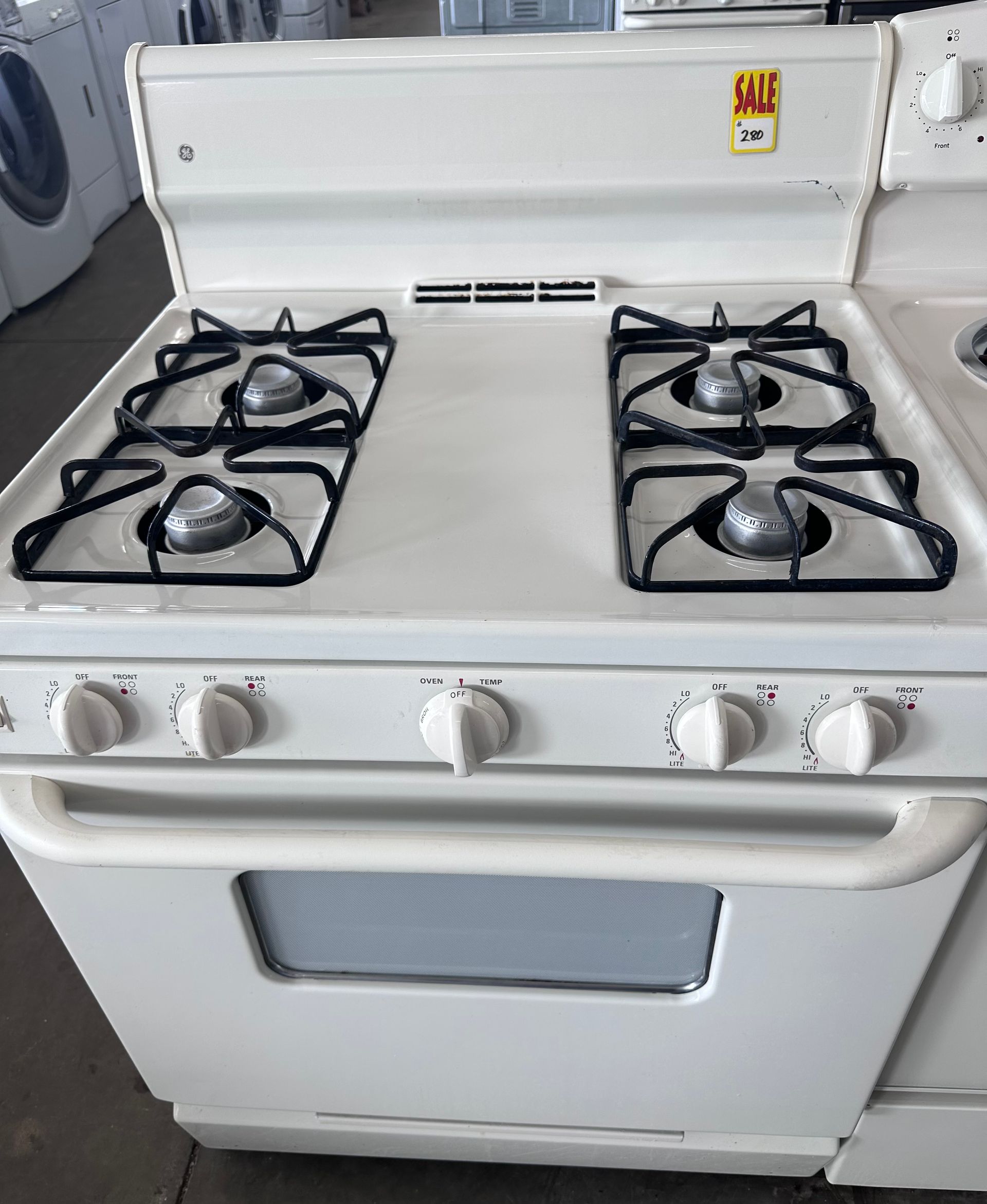 White gas range with four burners, oven, and control knobs.
