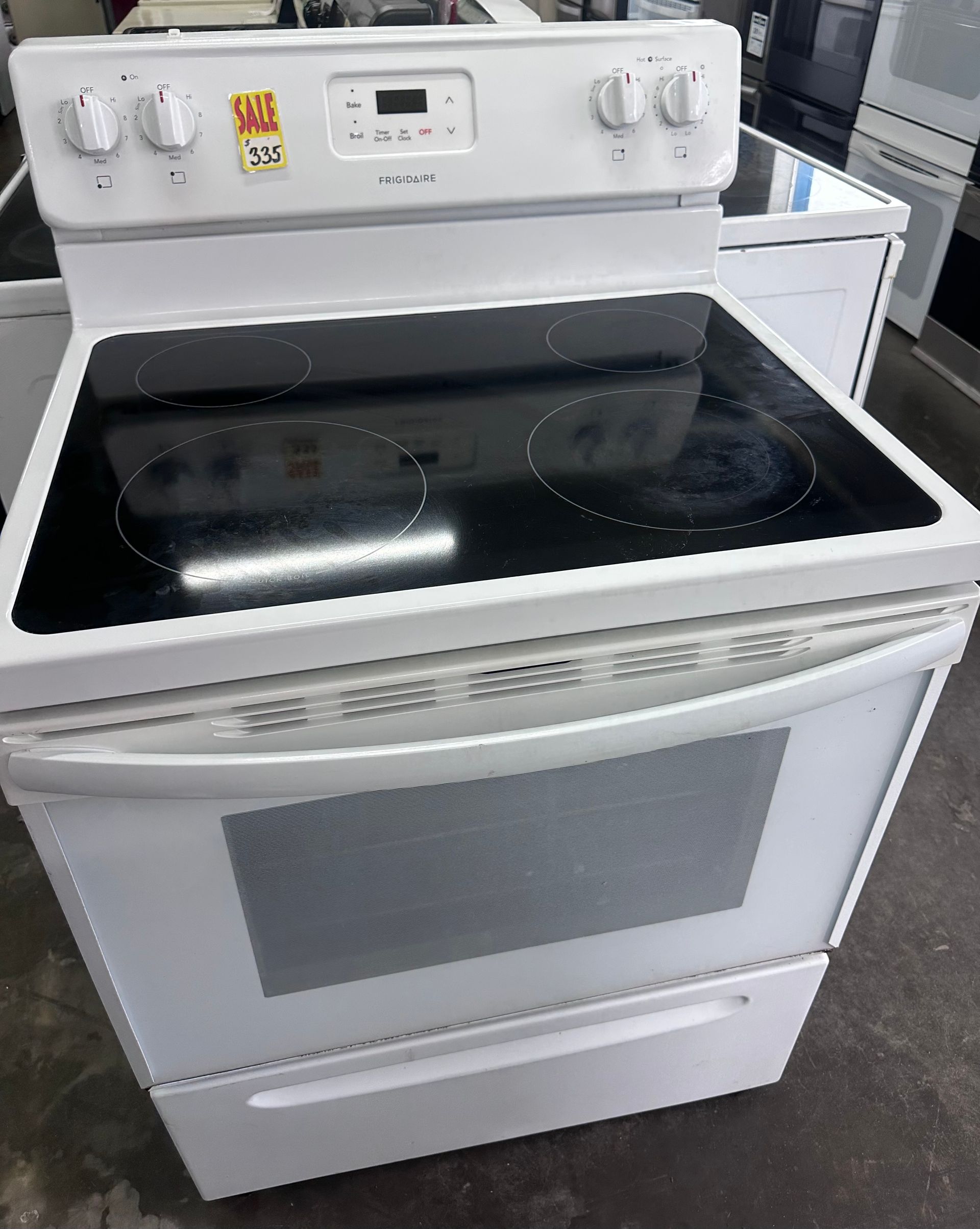White electric stove with black glass cooktop and oven door in a kitchen appliance store