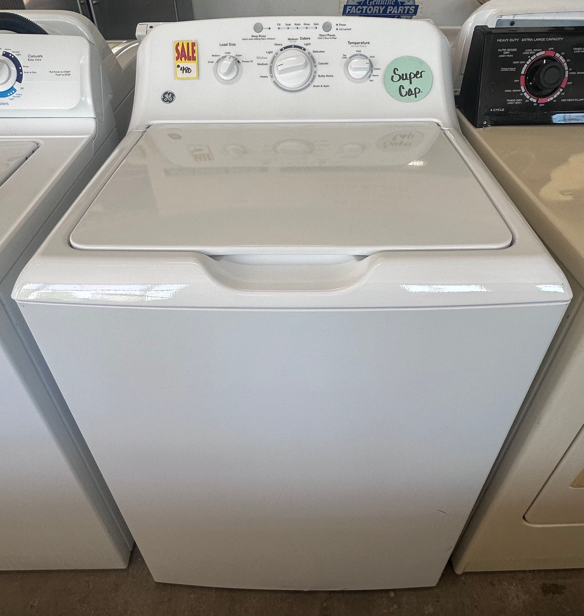LG washing machine on sale for $1,200, with a person reflected in the dark glass door.