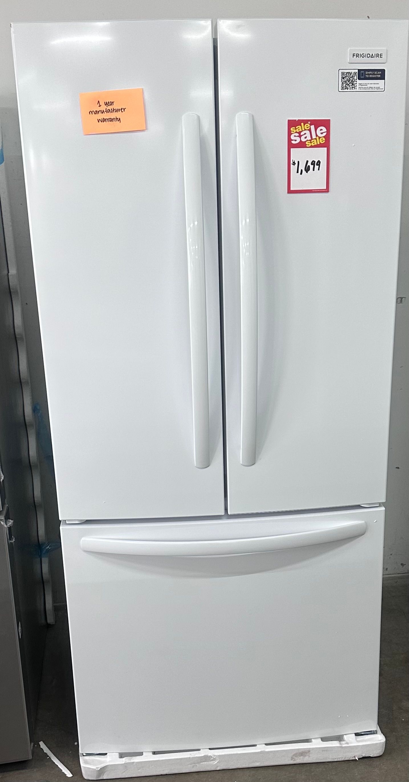 White French-door refrigerator with bottom freezer drawers and small labels on the doors