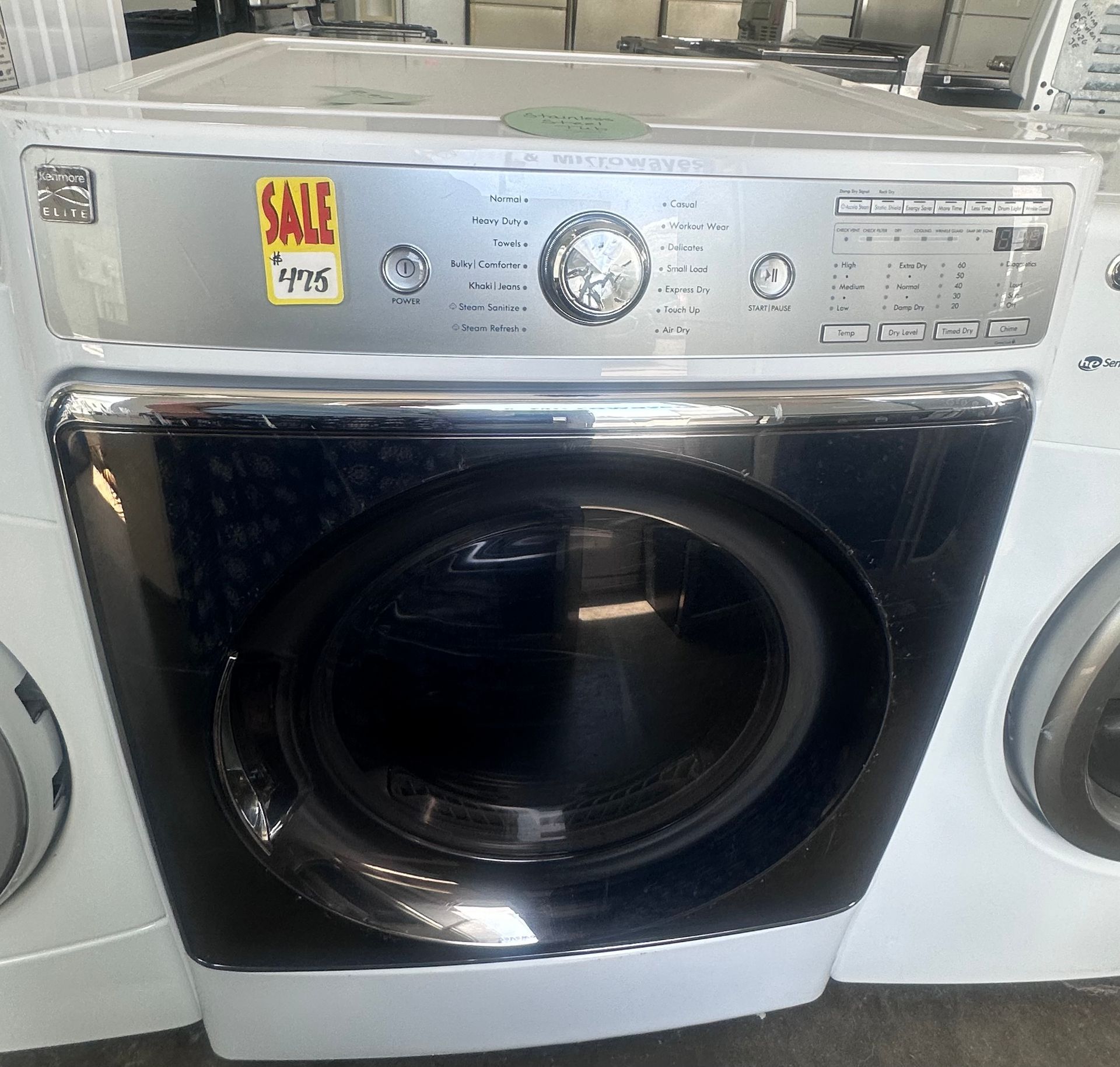 Silver front-load washer with a sale tag on the control panel in a laundry store
