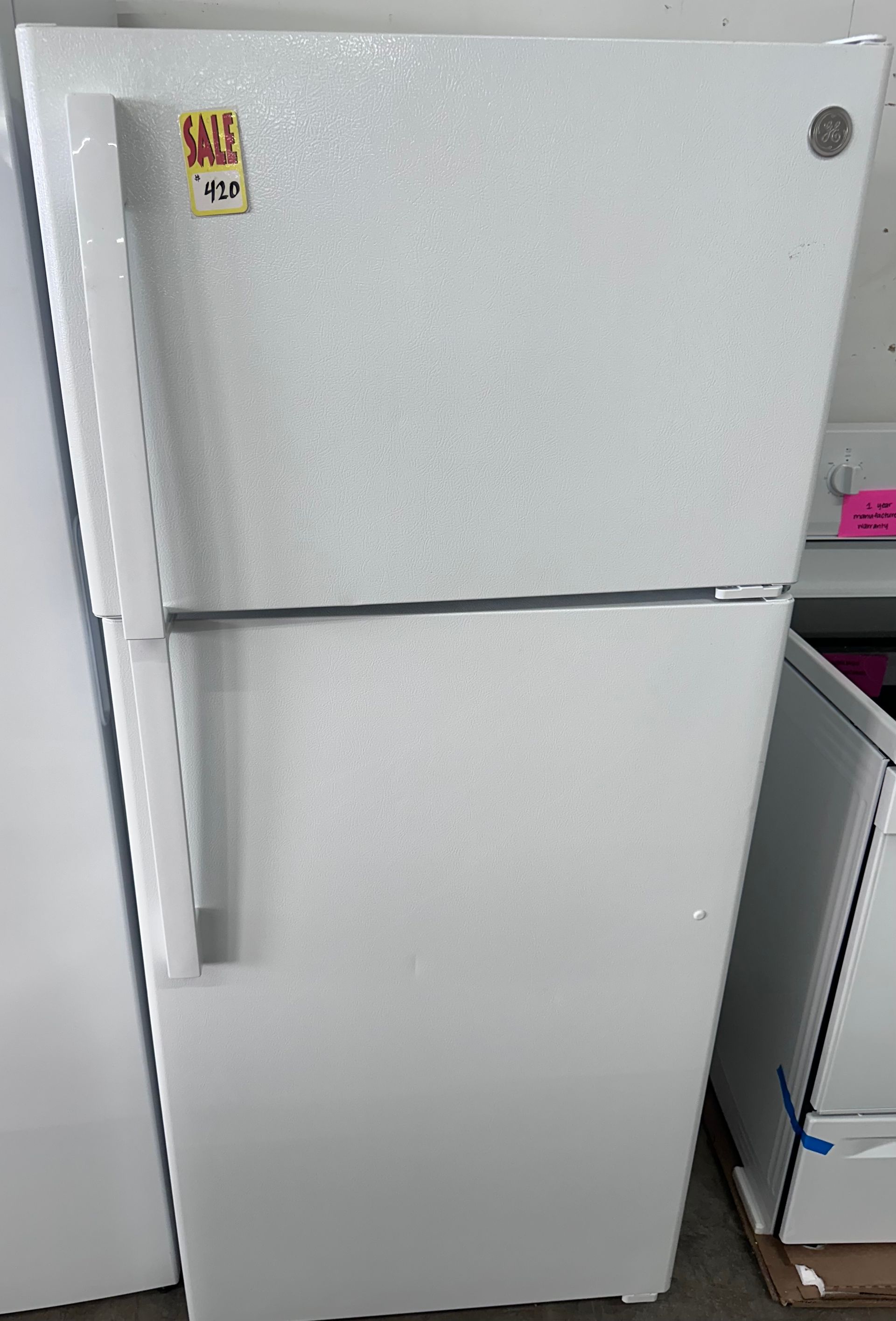 White refrigerator with bronze handles and price tags.