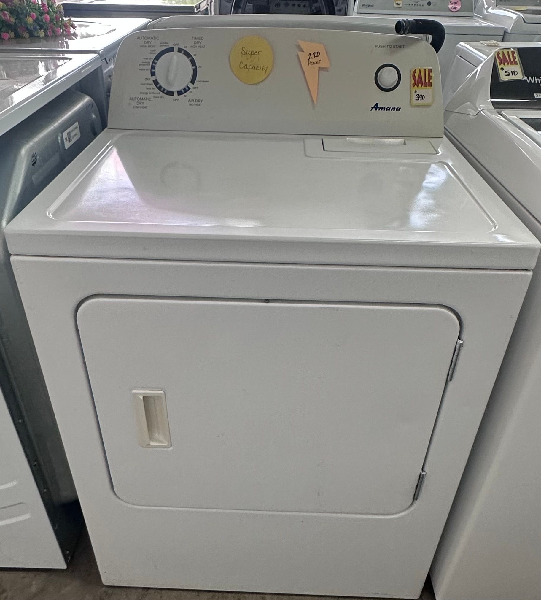 A white dryer is sitting on top of a counter next to a washer and dryer.