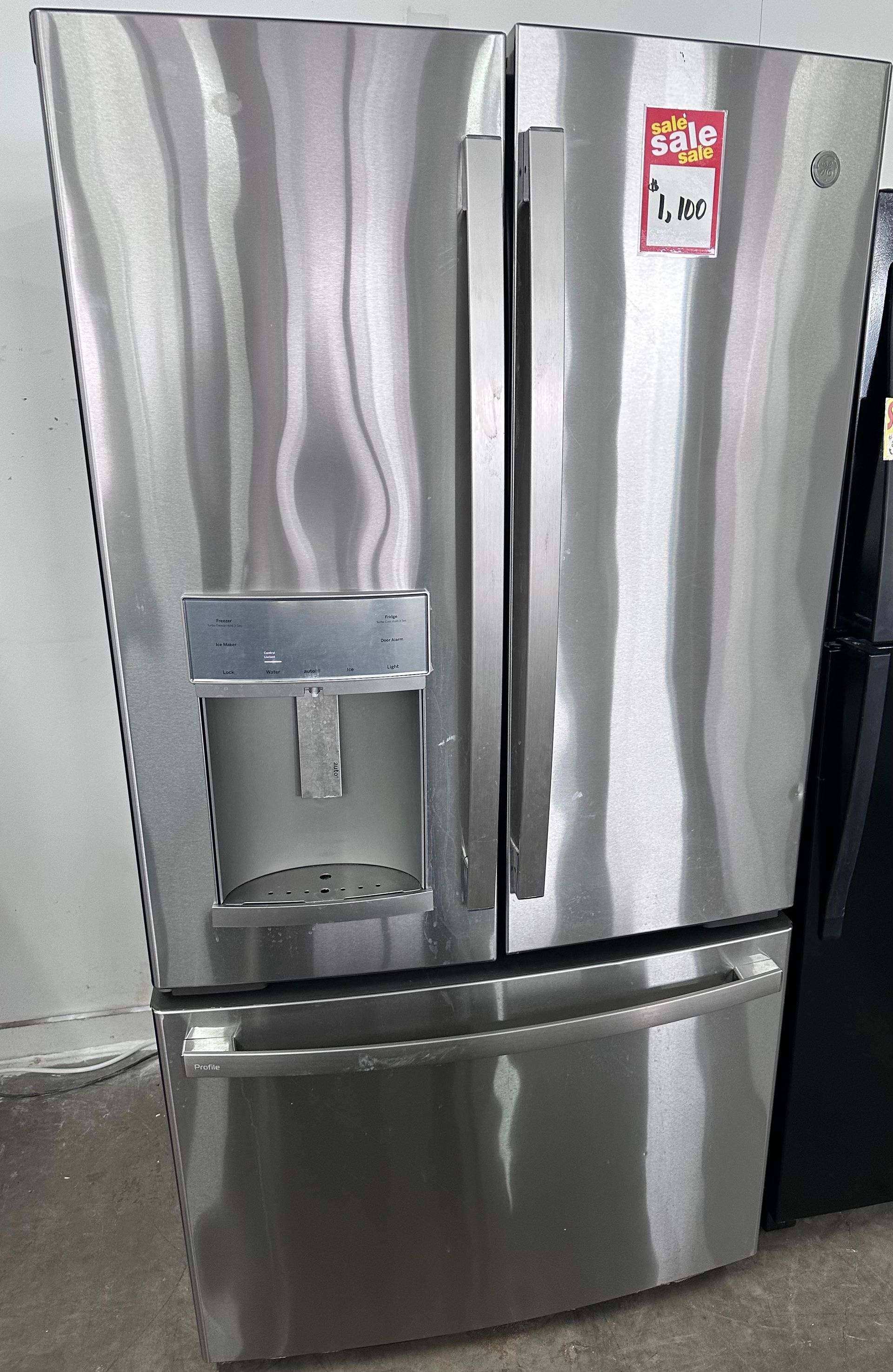 Stainless steel GE French door refrigerator with water dispenser and price tag.