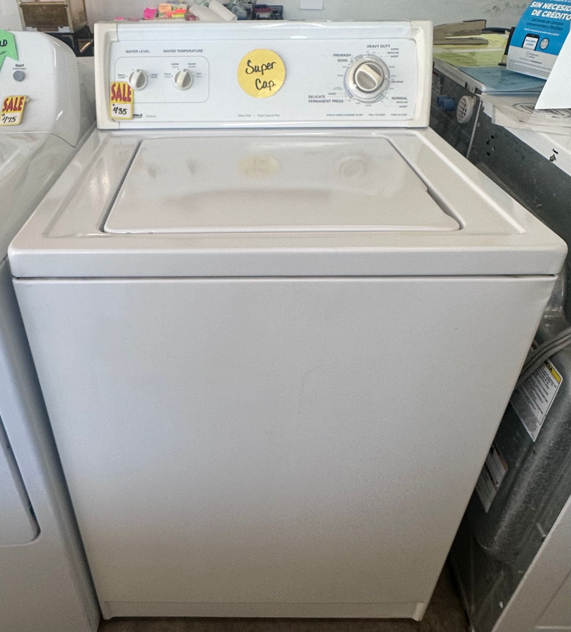 White top-loading washing machine with control panel in a laundry area.