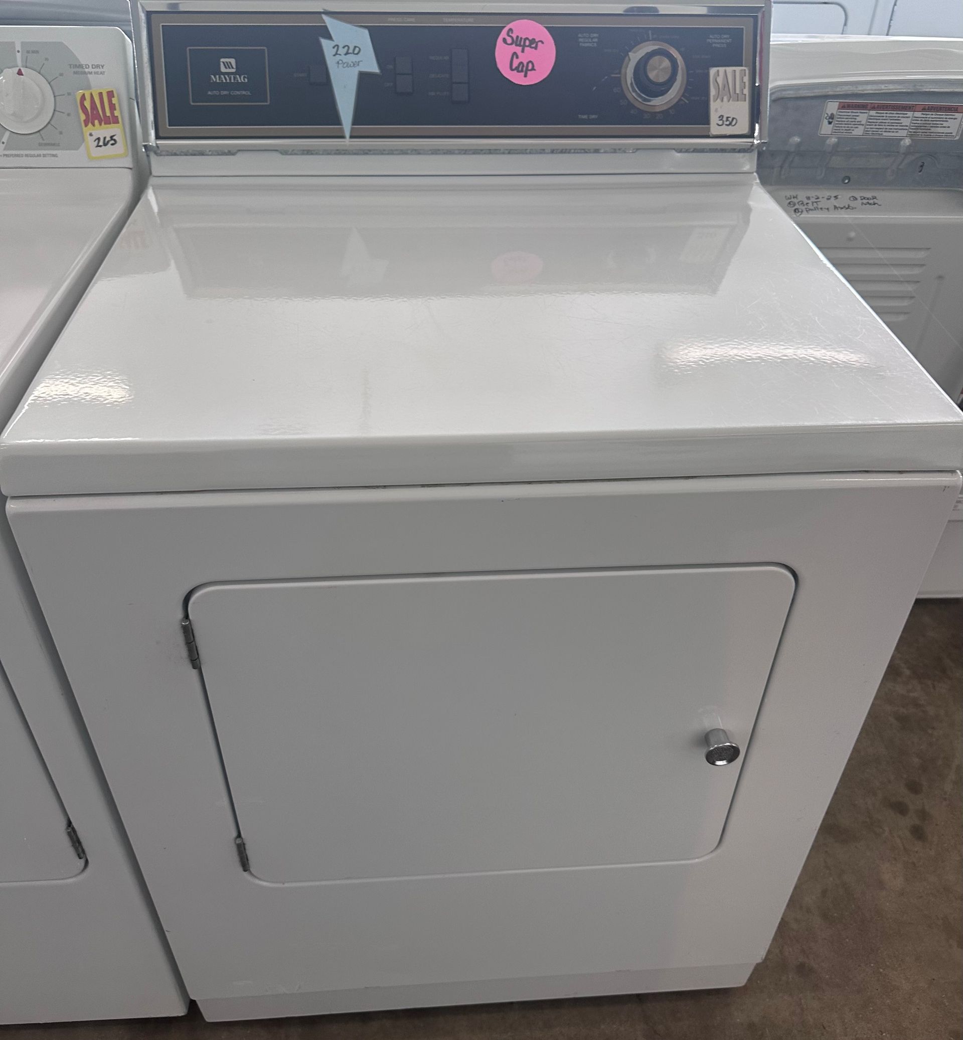 A white washing machine with a black door is sitting on the floor.