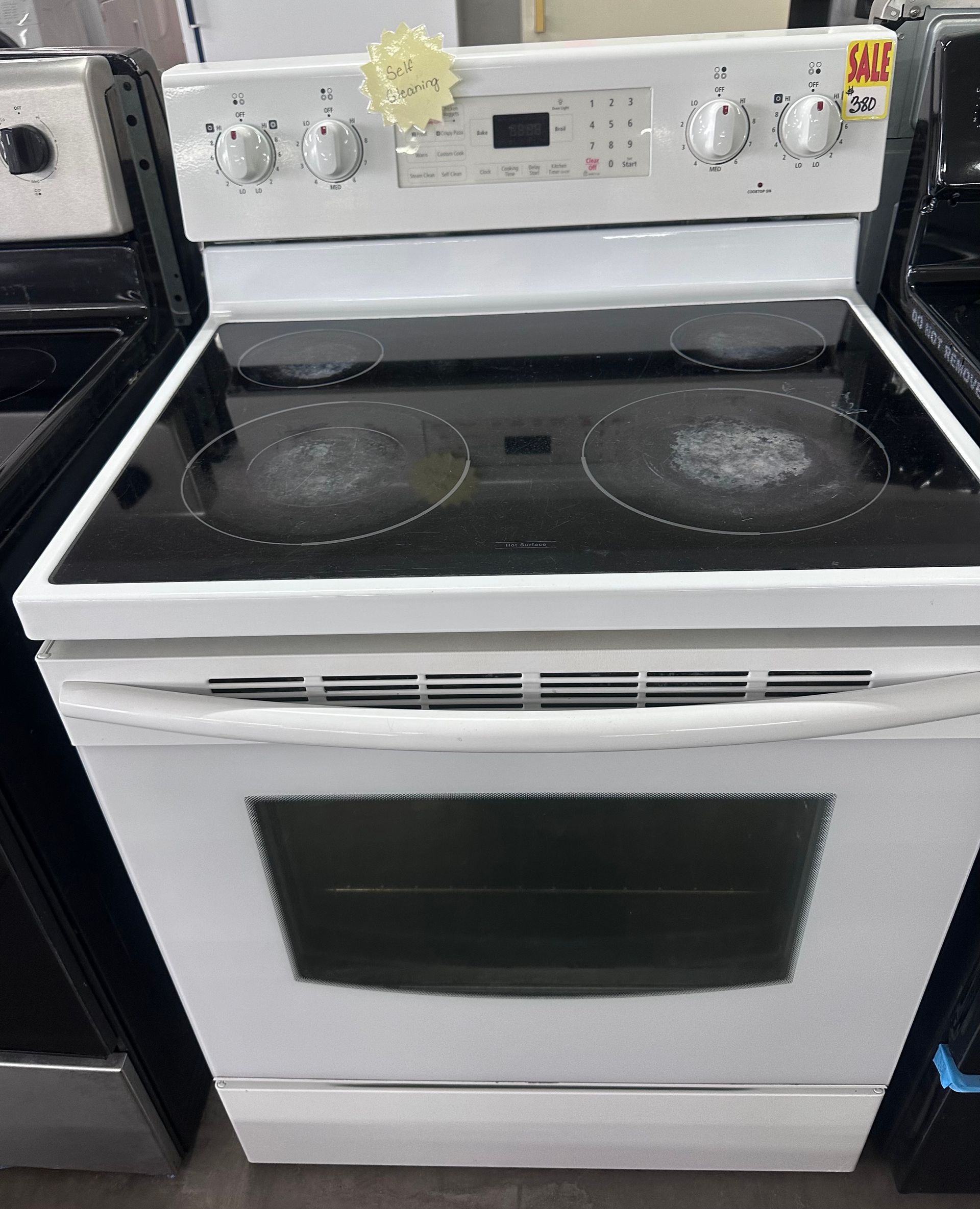 White electric stove with glass-top burners and oven door in a kitchen.
