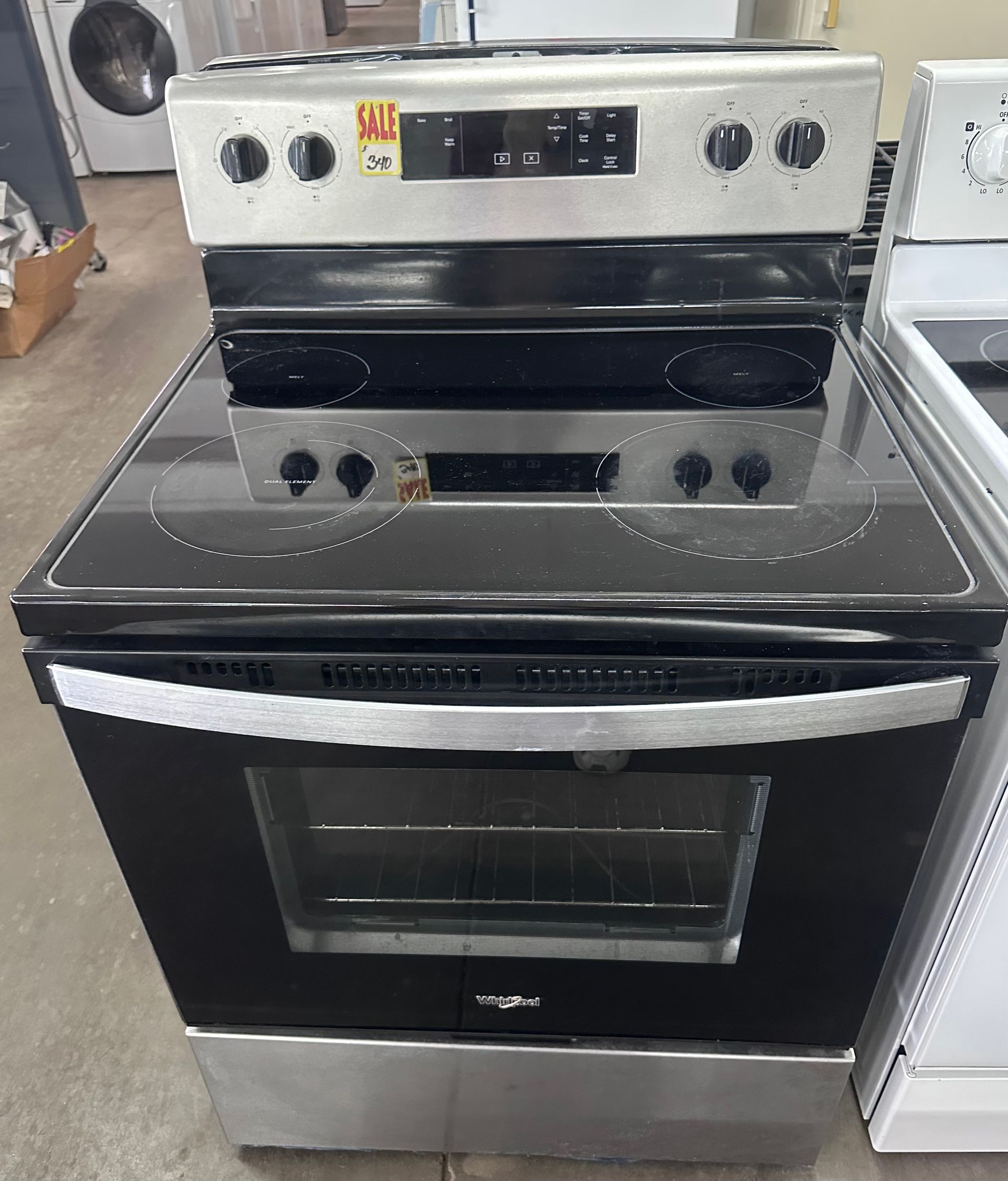 Black electric stove with stainless steel control panel in a kitchen appliance display.
