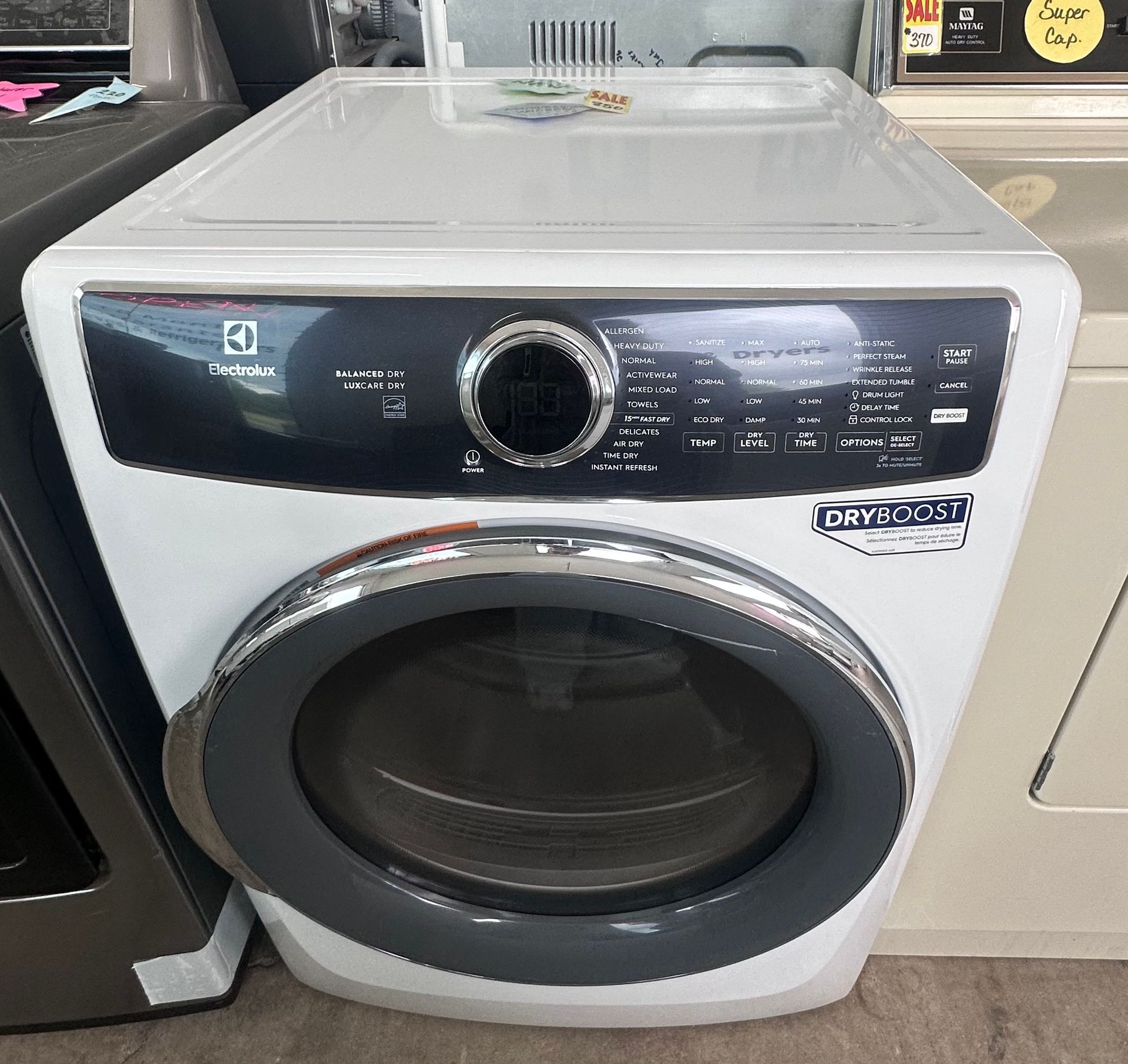 White front-load washer with black control panel displayed in a store aisle