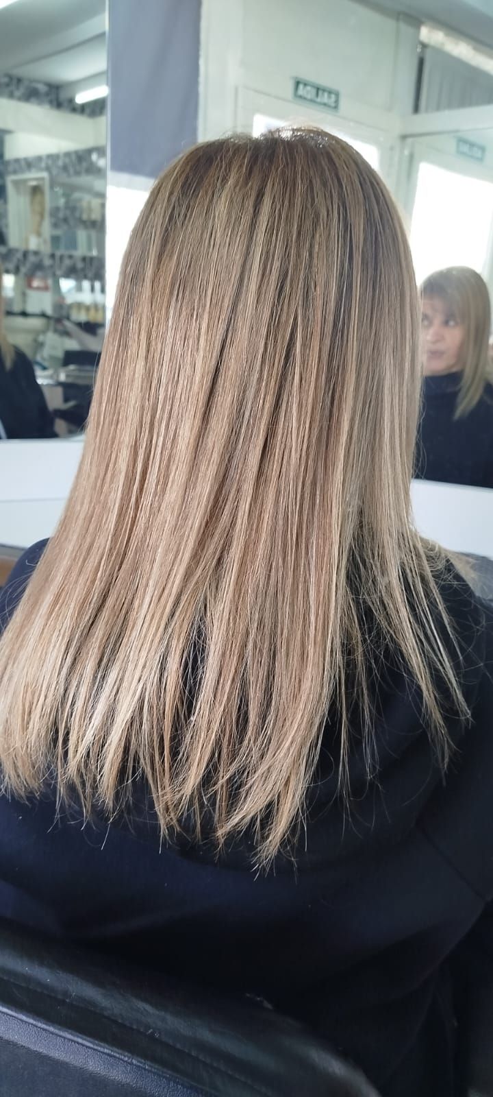 Cabello de mujer con estilo rizado, tonos castaño claro y dorado, en salón.