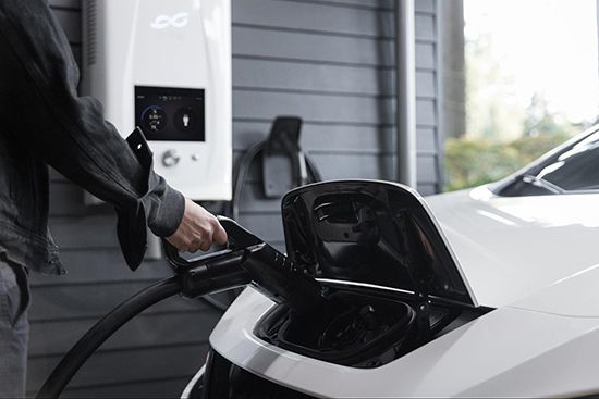 Person charging a white electric car at a public charging station