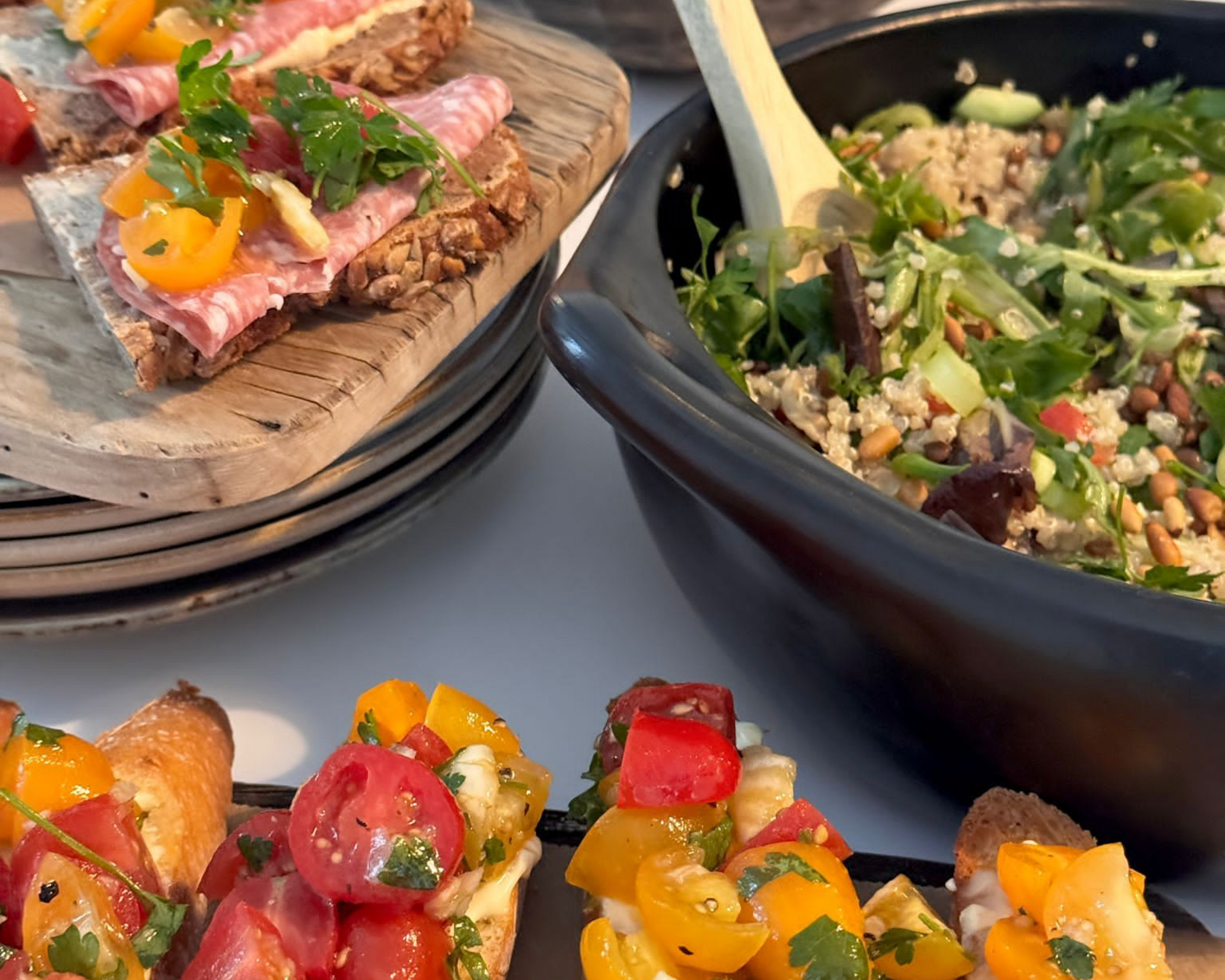 Voorgerechten: salami crackers, tomatenbruschetta, quinoasalade in een zwarte kom.
