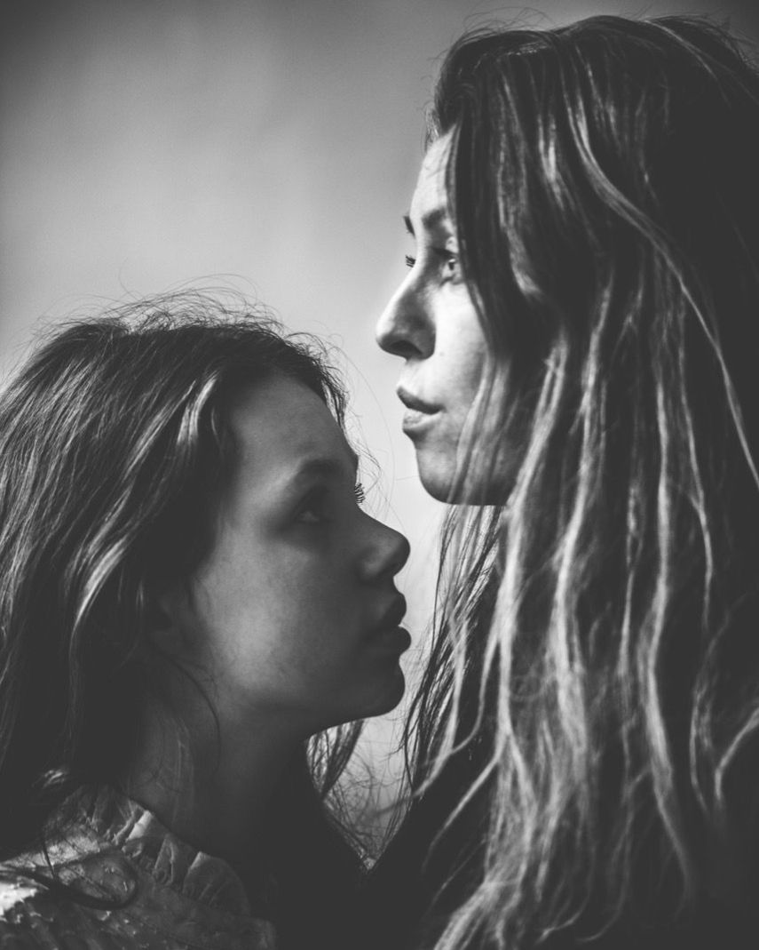 Twee vrouwen staan dicht tegenover elkaar, in zwart-wit. De ene kijkt naar beneden, de andere naar voren.