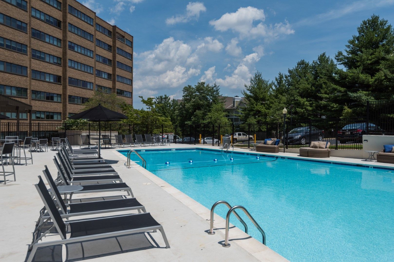 A large swimming pool surrounded by chairs and umbrellas in front of a building at The Mark by Solaire in Alexandria, VA.