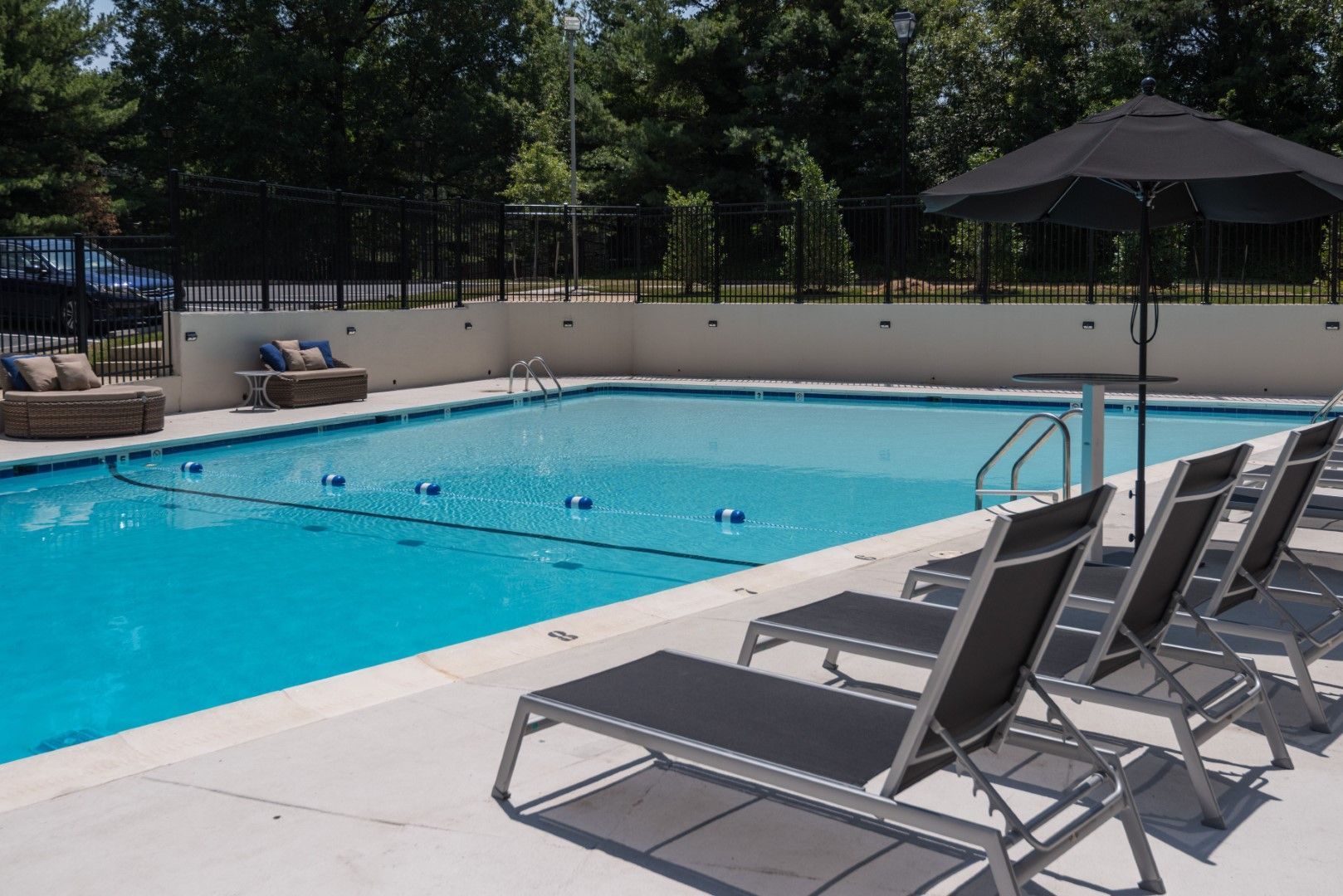 A large swimming pool with chairs and umbrellas around it at The Mark by Solaire in Alexandria, VA.