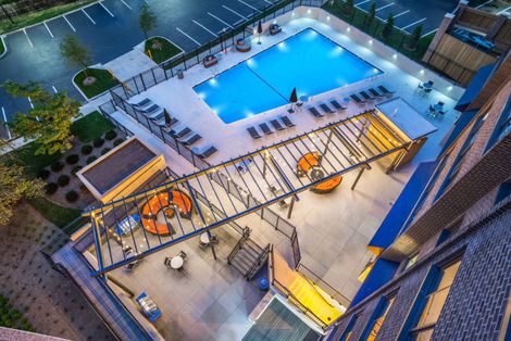 An aerial view of a large swimming pool at night at The Mark by Solaire Apartments for rent in Alexandria, VA.