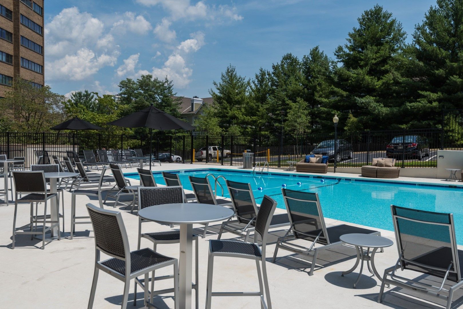 A large swimming pool with tables and chairs around it at The Mark by Solaire in Alexandria, VA.