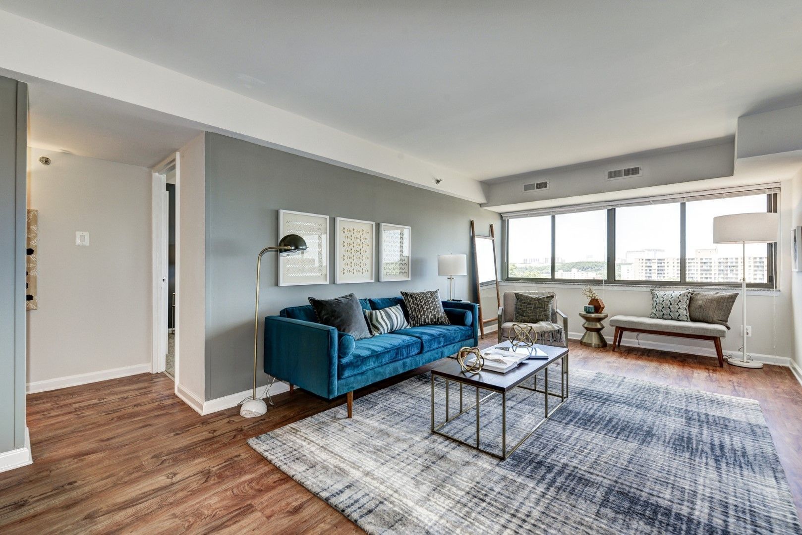 A living room with a blue couch , two chairs , a coffee table and a rug at The Mark by Solaire in Alexandria, VA.