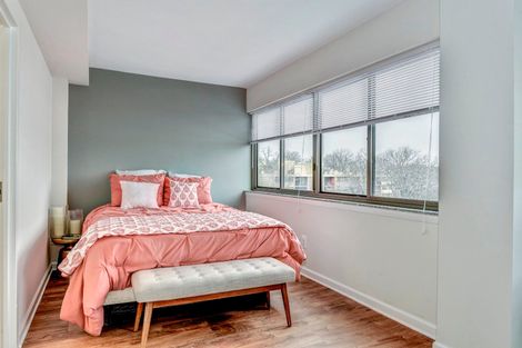 A bedroom with a bed , bench , and window at The Mark by Solaire Apartments for rent in Alexandria, VA.