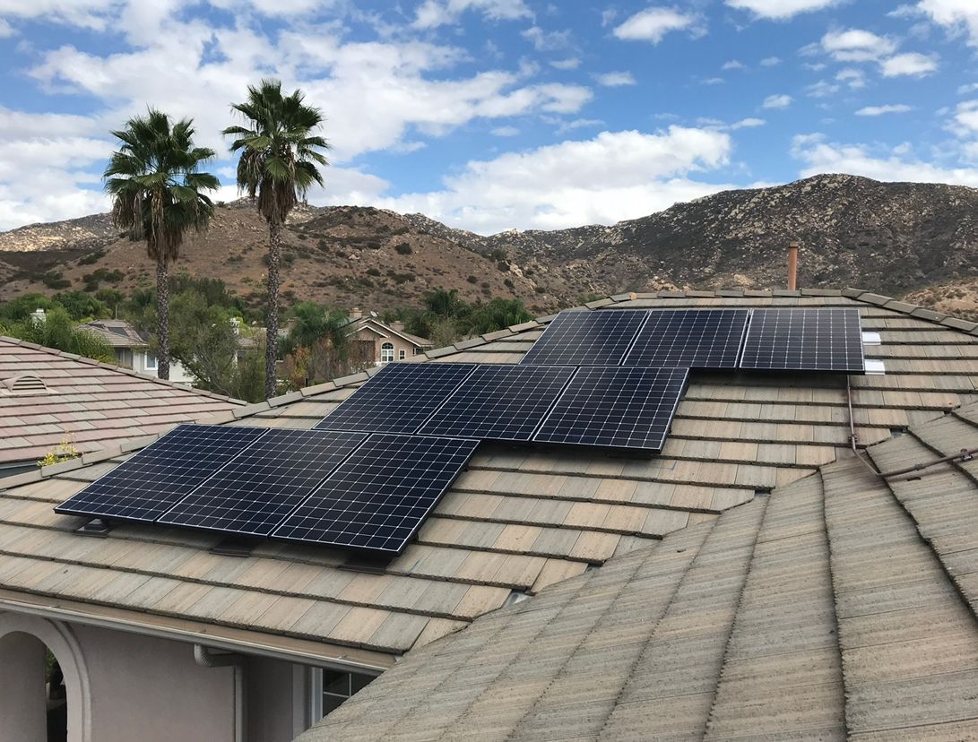 A roof with solar panels on it and mountains in the background.