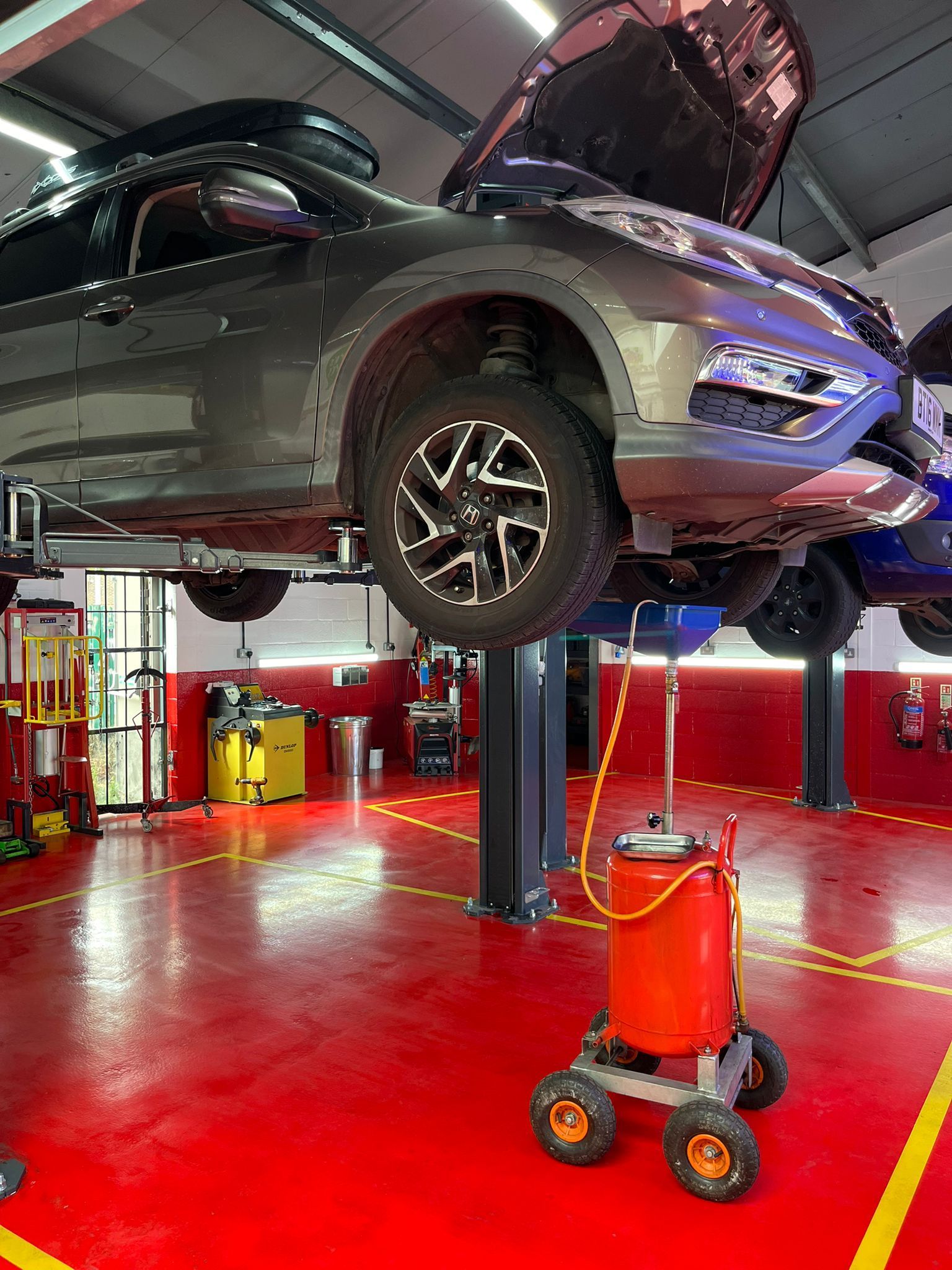 A car is sitting on a lift in a garage with the hood up.