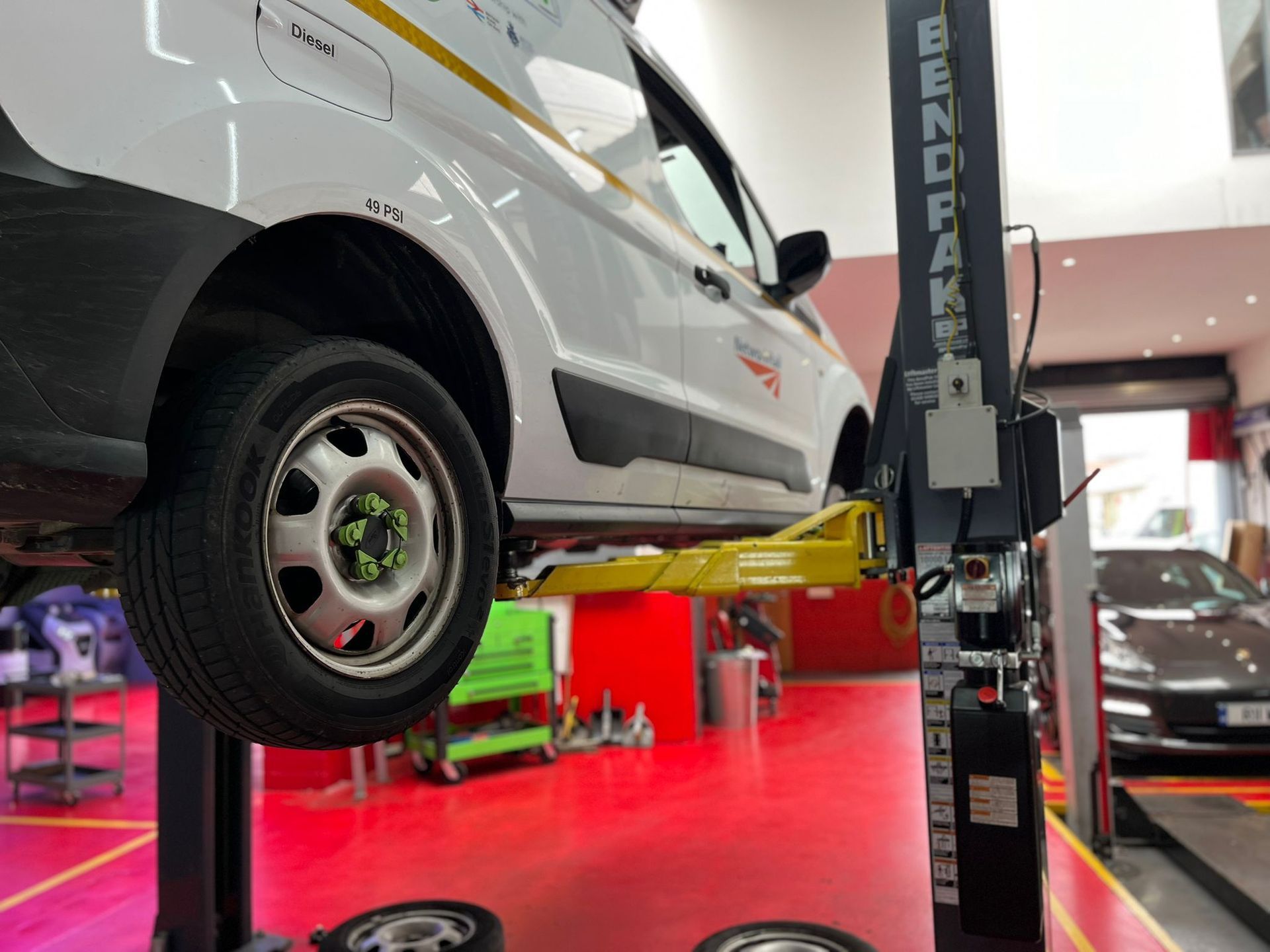 A white van is sitting on top of a lift in a garage.