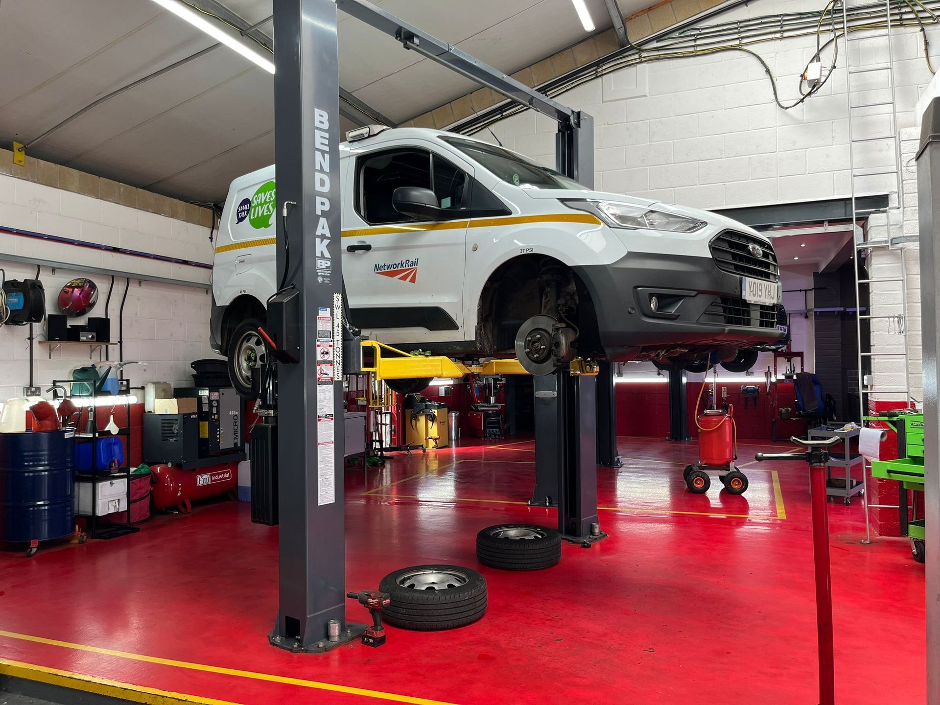 A white van is sitting on a lift in a garage.