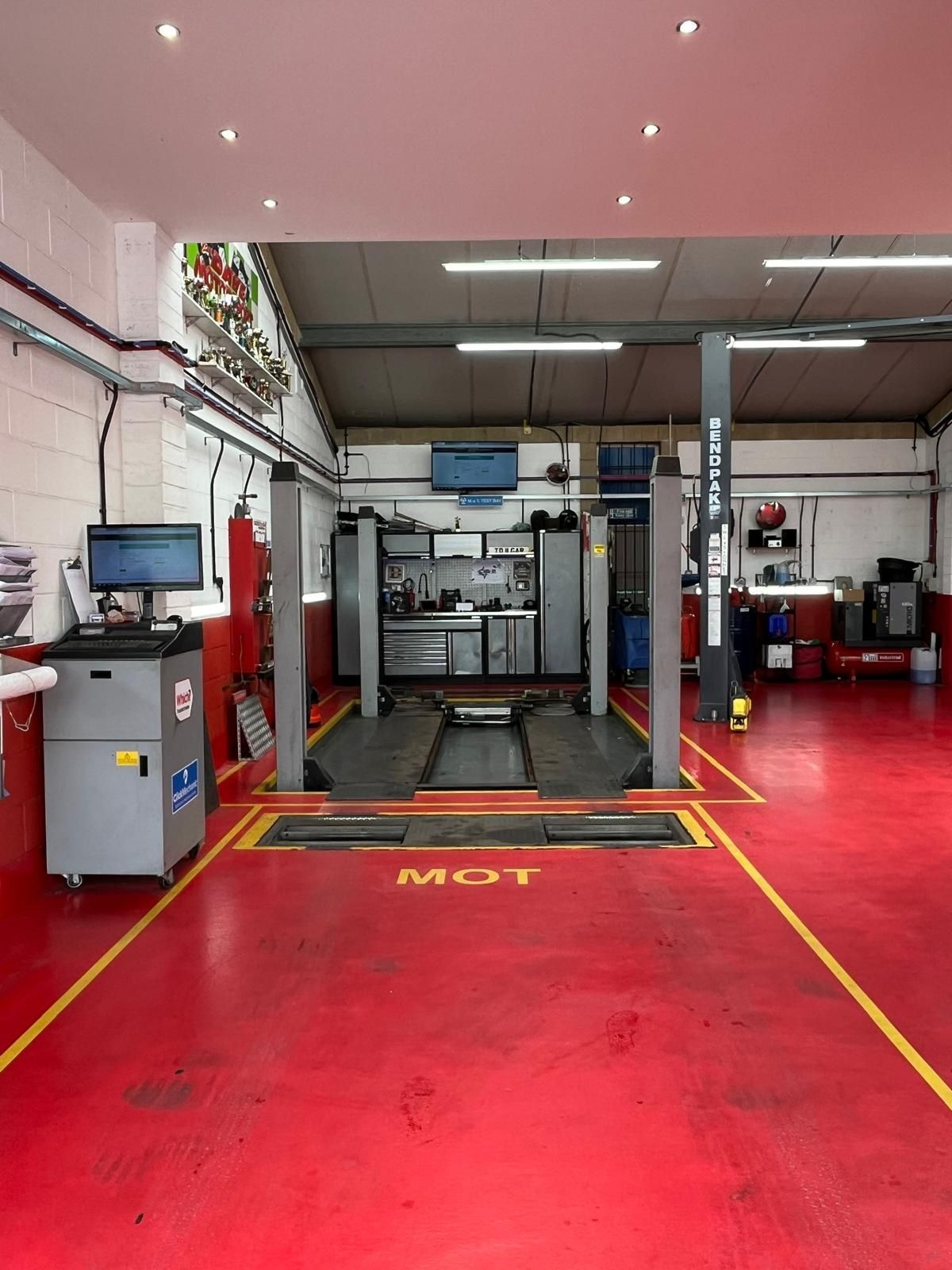 The inside of a garage with a red floor and yellow lines.