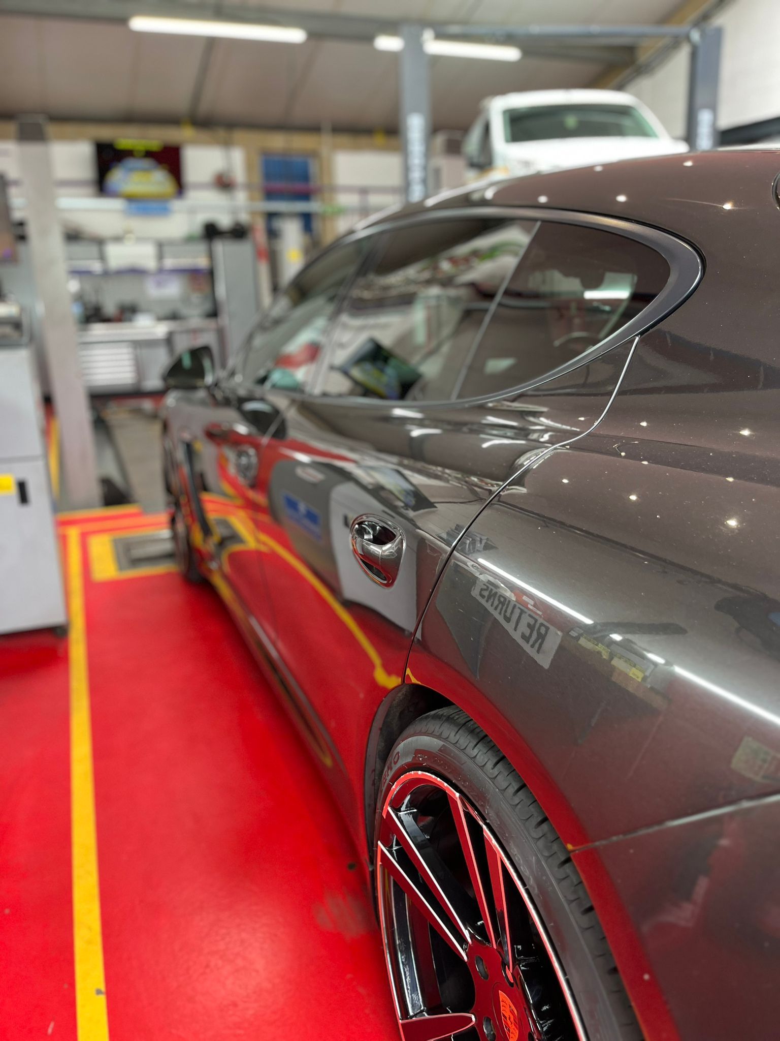 A car is parked on a red floor in a garage.