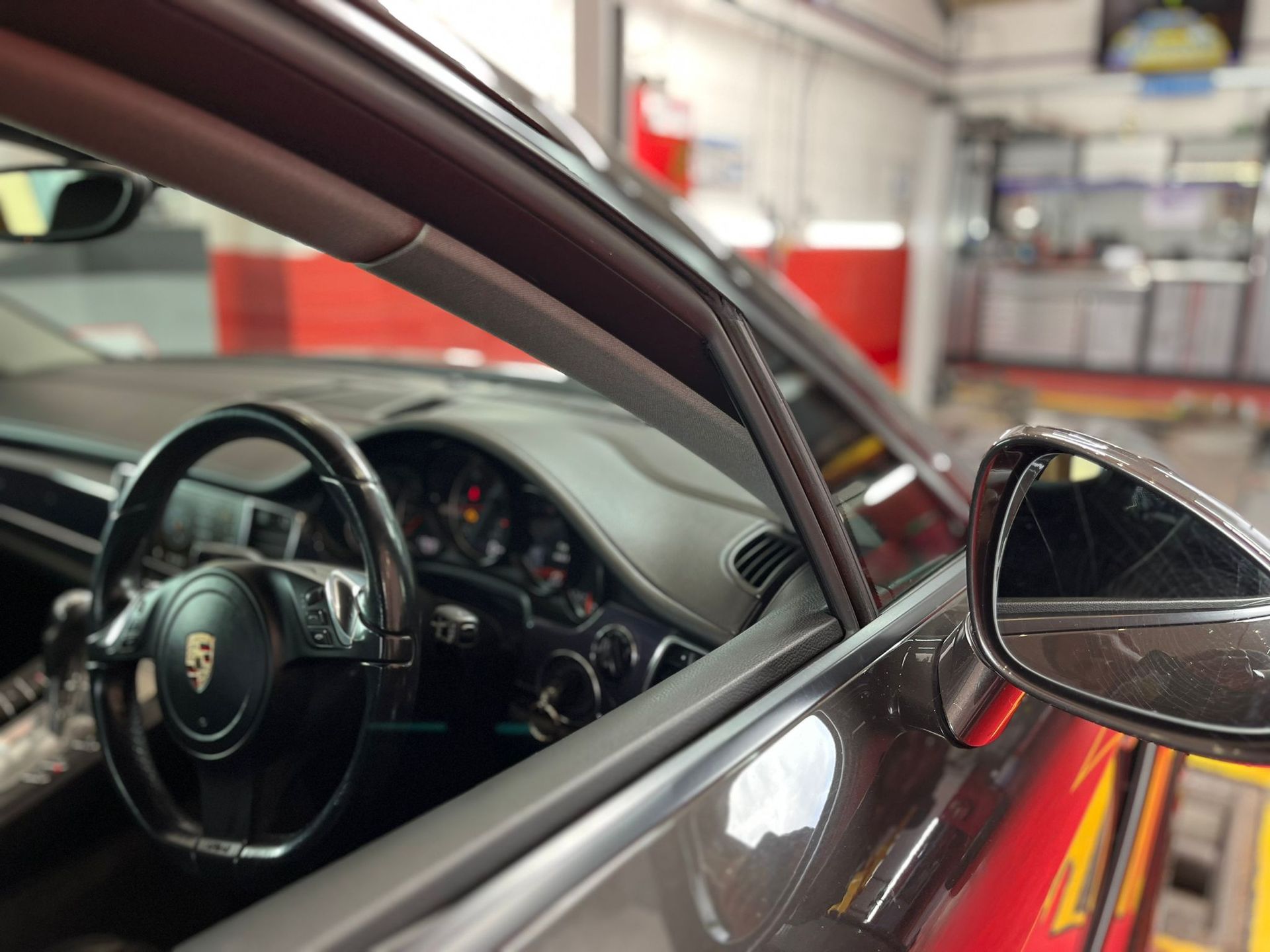 A porsche car is parked in a garage with the door open